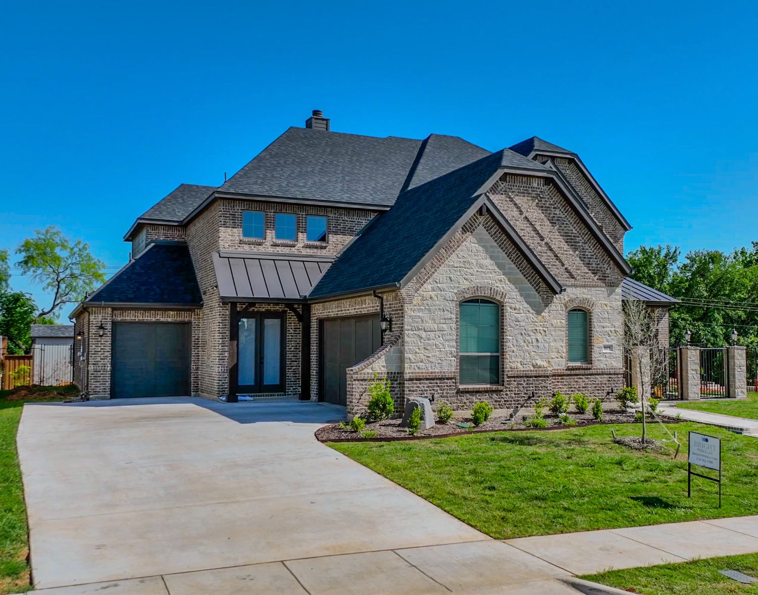 Modern stone house with dark roof and attached garage featuring elegant architectural details.