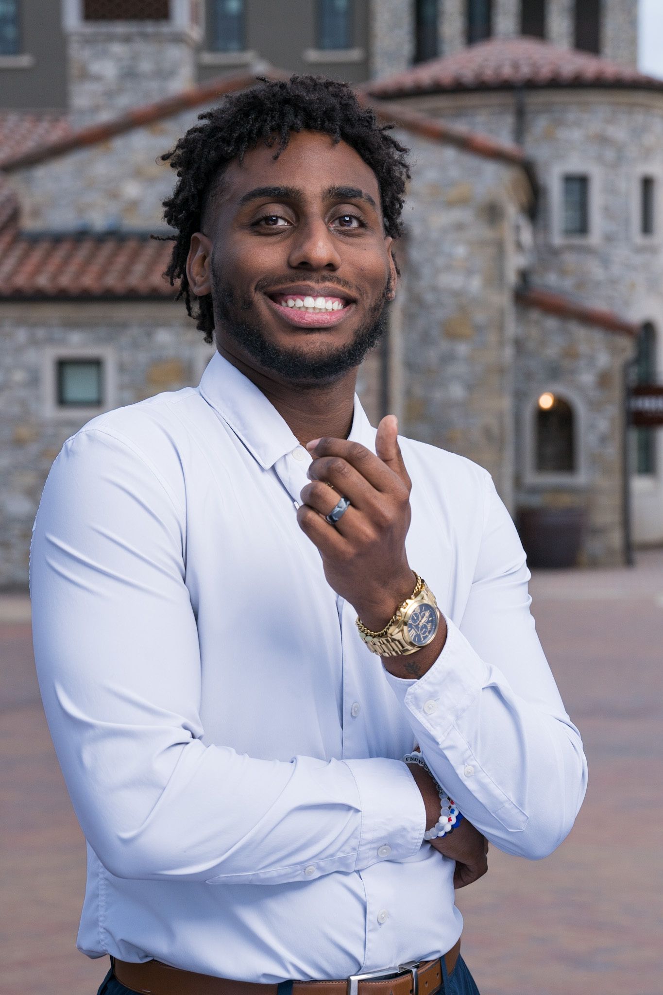 Professional portrait in crisp white shirt and gold watch against stone architecture.
