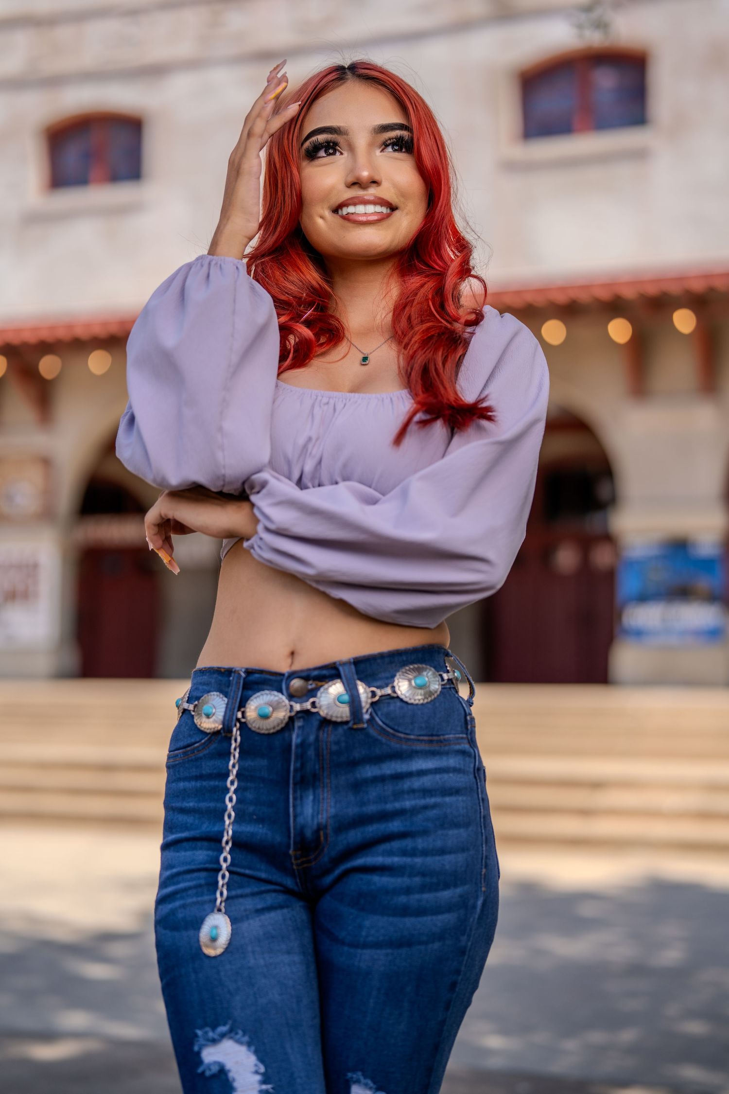 Street style fashion photo showcasing purple peasant top and concho belt against urban backdrop.