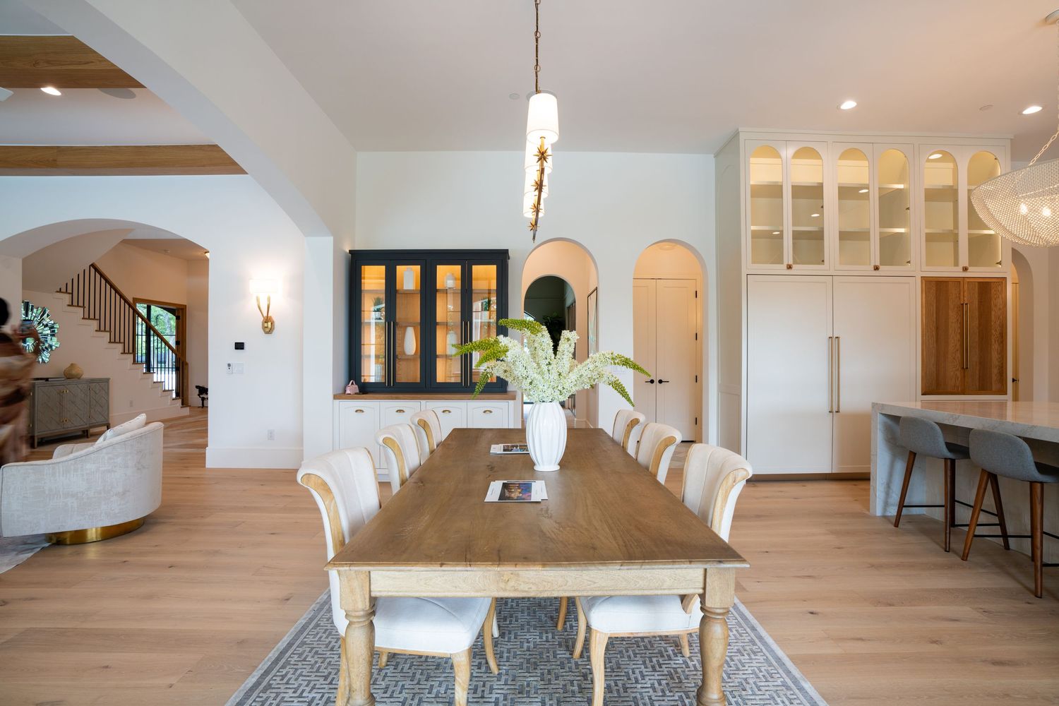 Elegant dining area with wooden table and modern pendant lighting in an open floor plan.