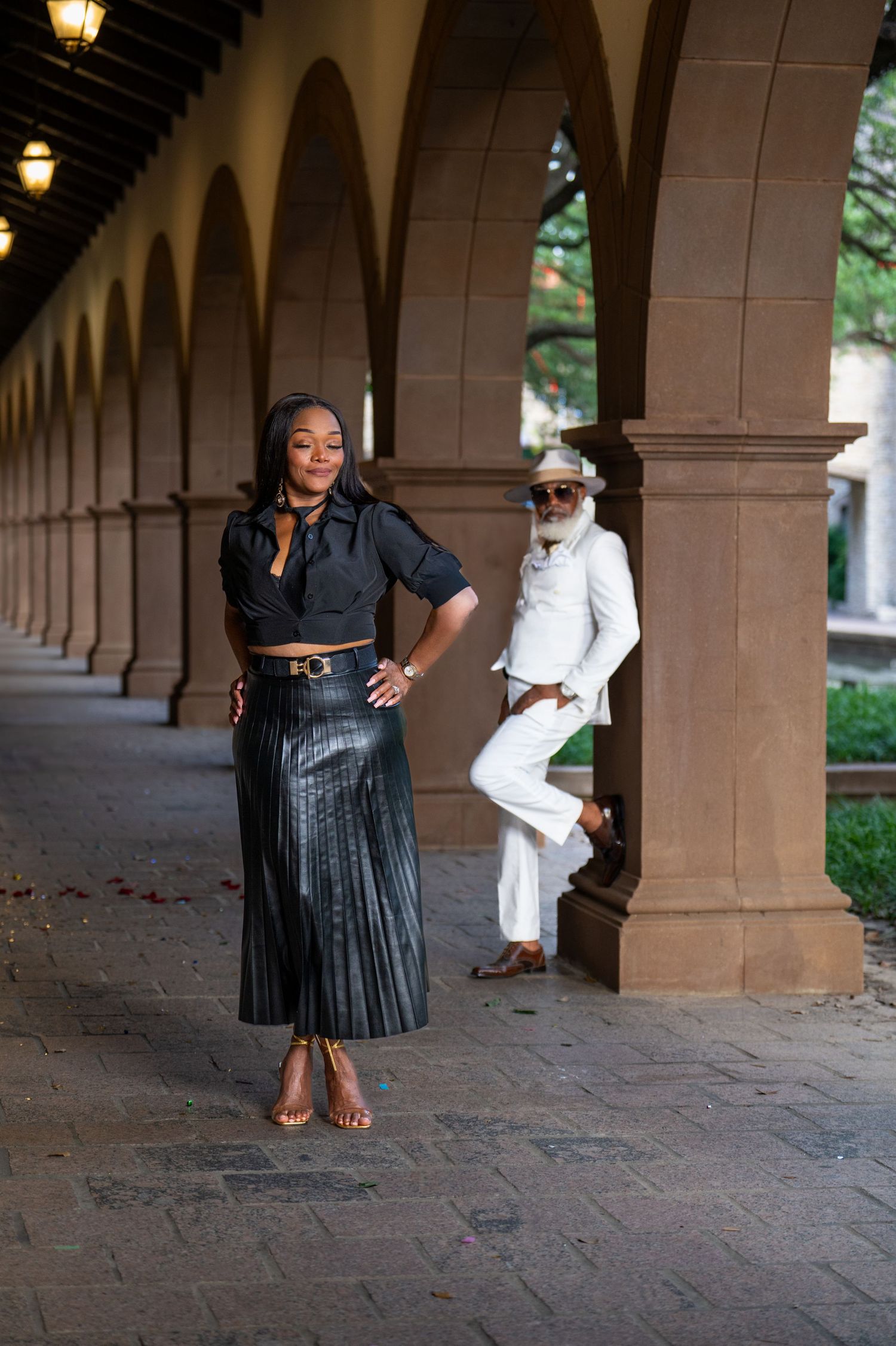Fashion shoot in arched hallway features elegant couple in black and white coordinated outfits.