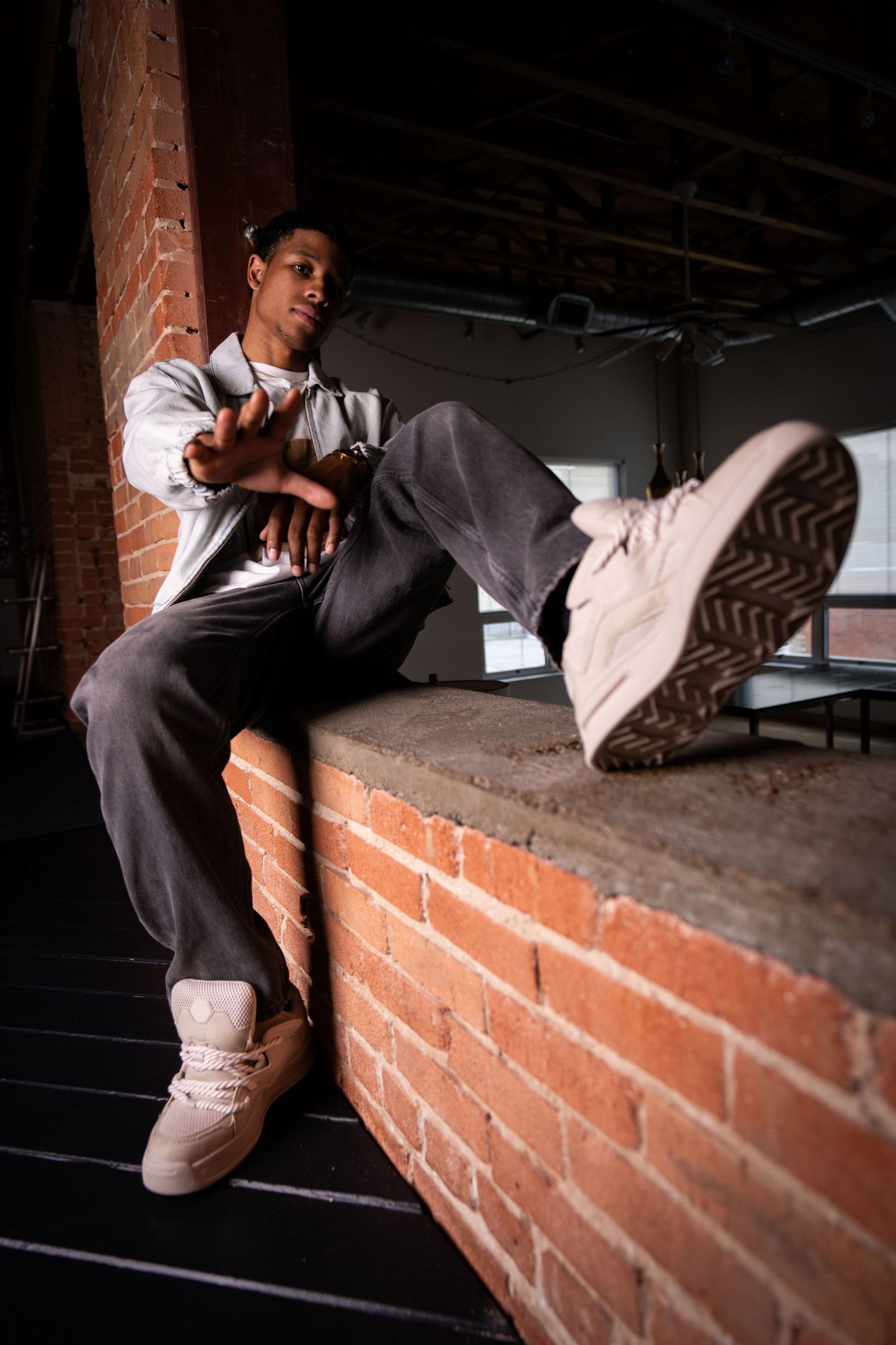 Urban fashion photo on brick ledge showcasing casual streetwear and sneakers.