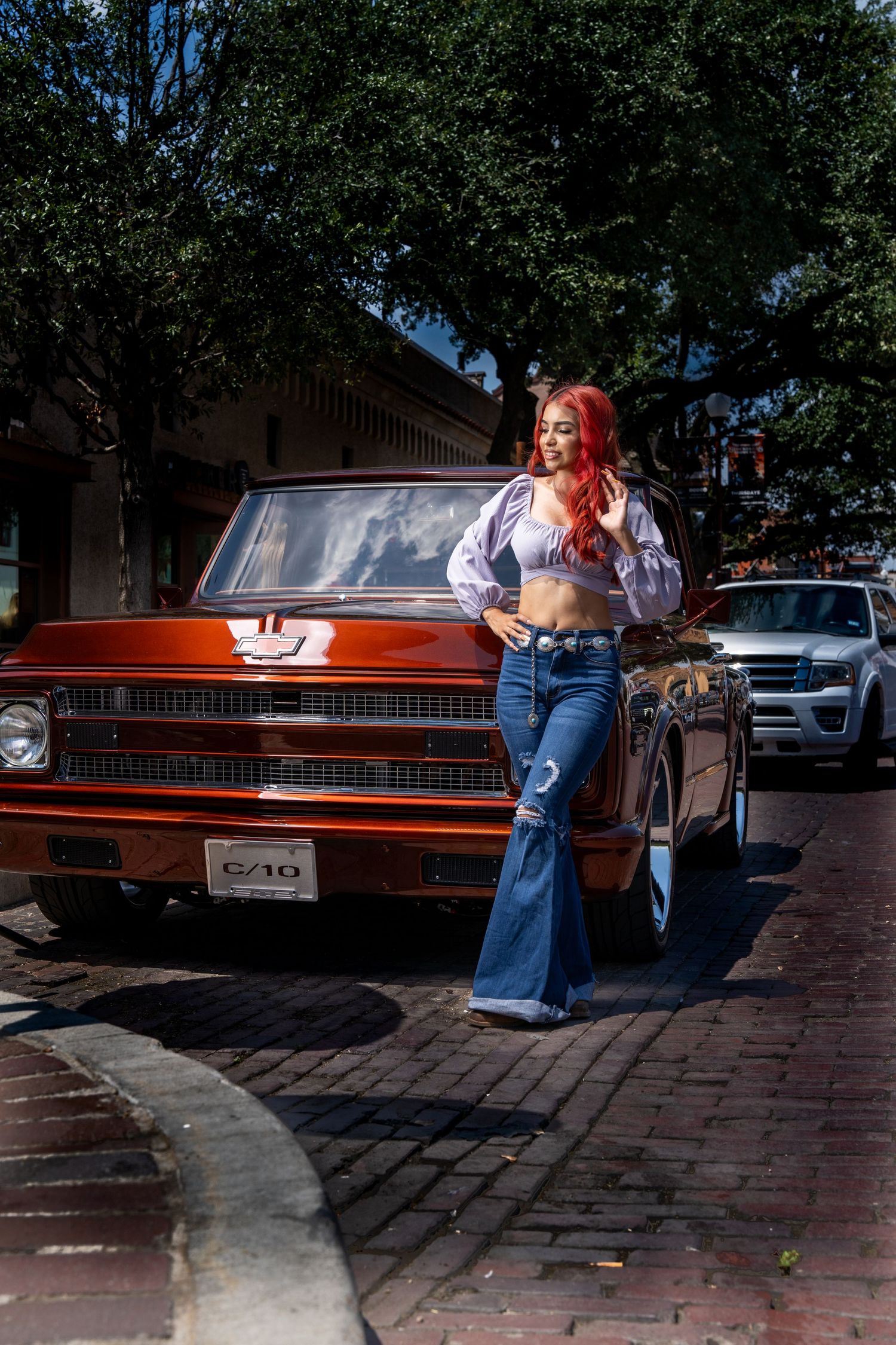 Vintage fashion shoot with orange Chevrolet truck on brick paved street.