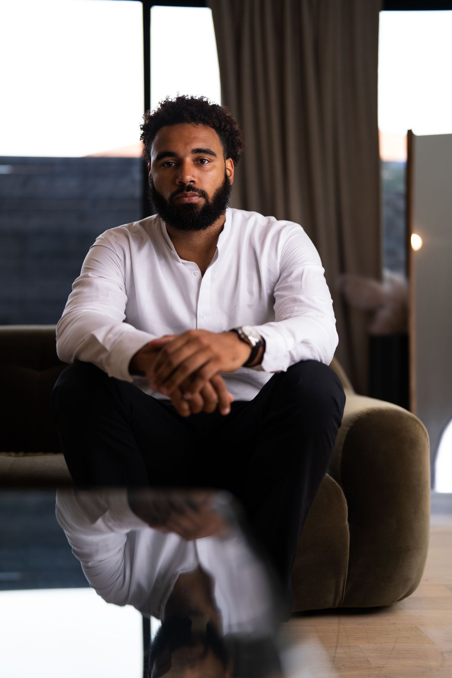 Casual portrait in white henley shirt against modern interior setting.