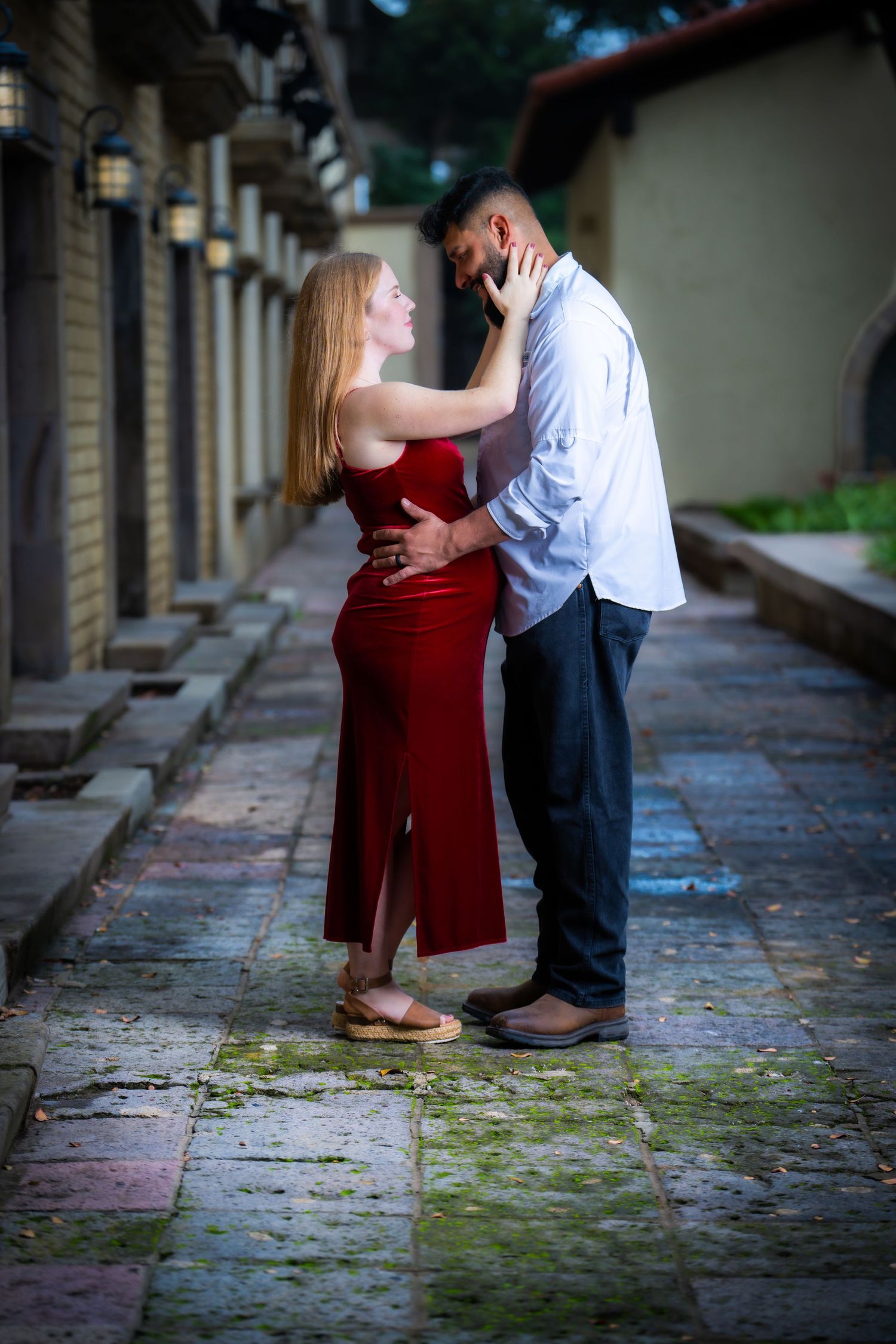 A tender moment between a couple on a historic stone walkway with vintage lampposts.