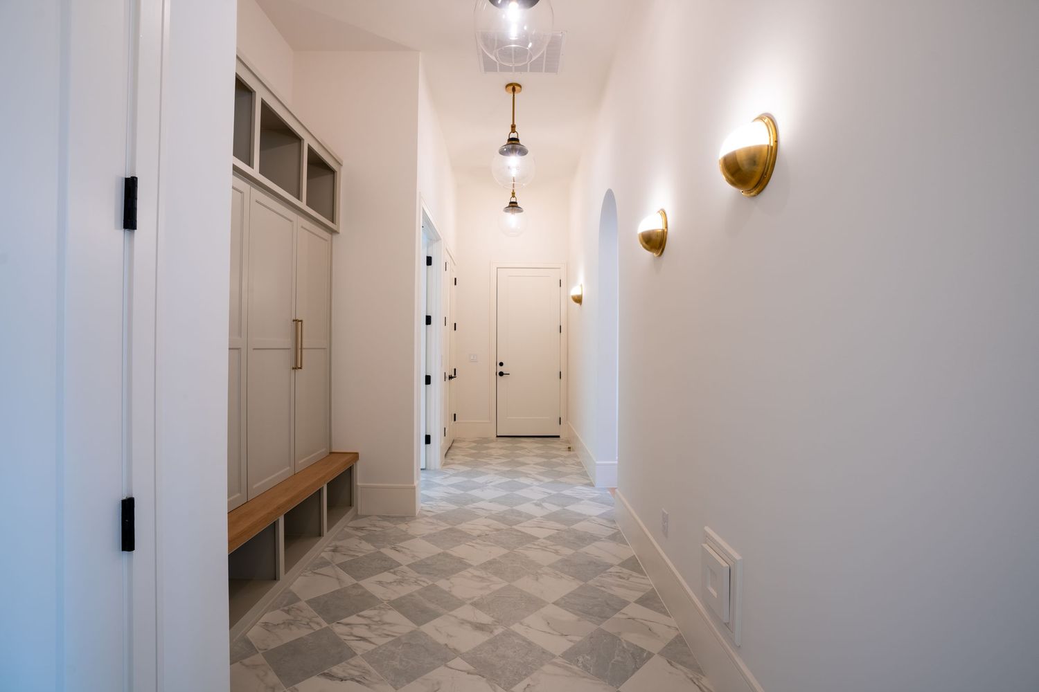 Long white hallway with geometric floor pattern and modern light fixtures.