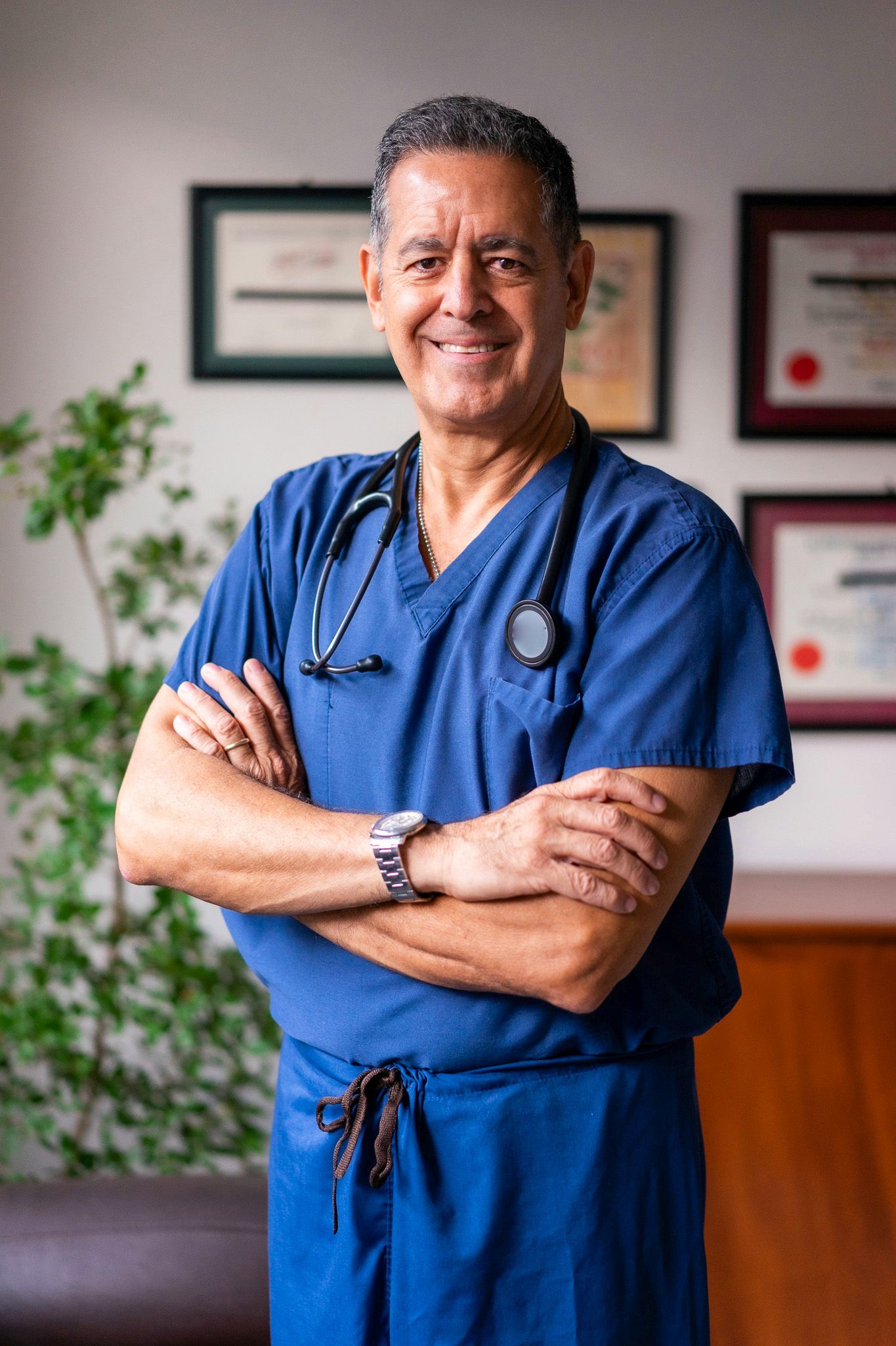 Healthcare professional in blue scrubs standing confidently with stethoscope.
