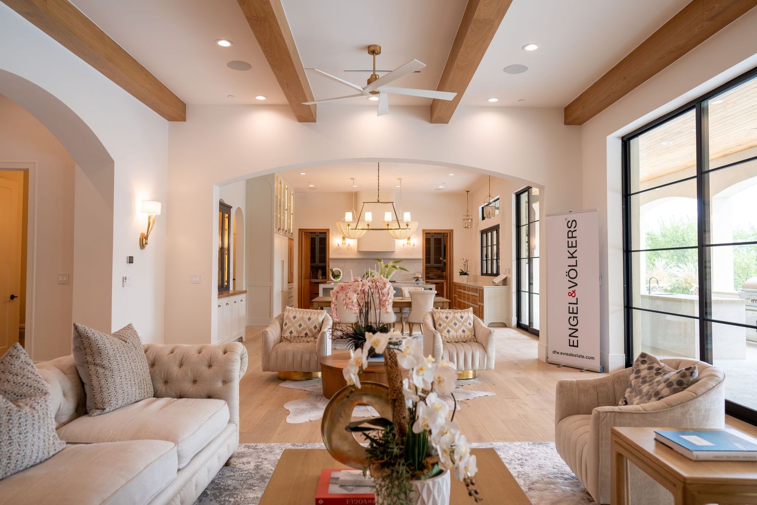 Elegant living and dining area with wooden beam ceiling, archways, and comfortable seating.