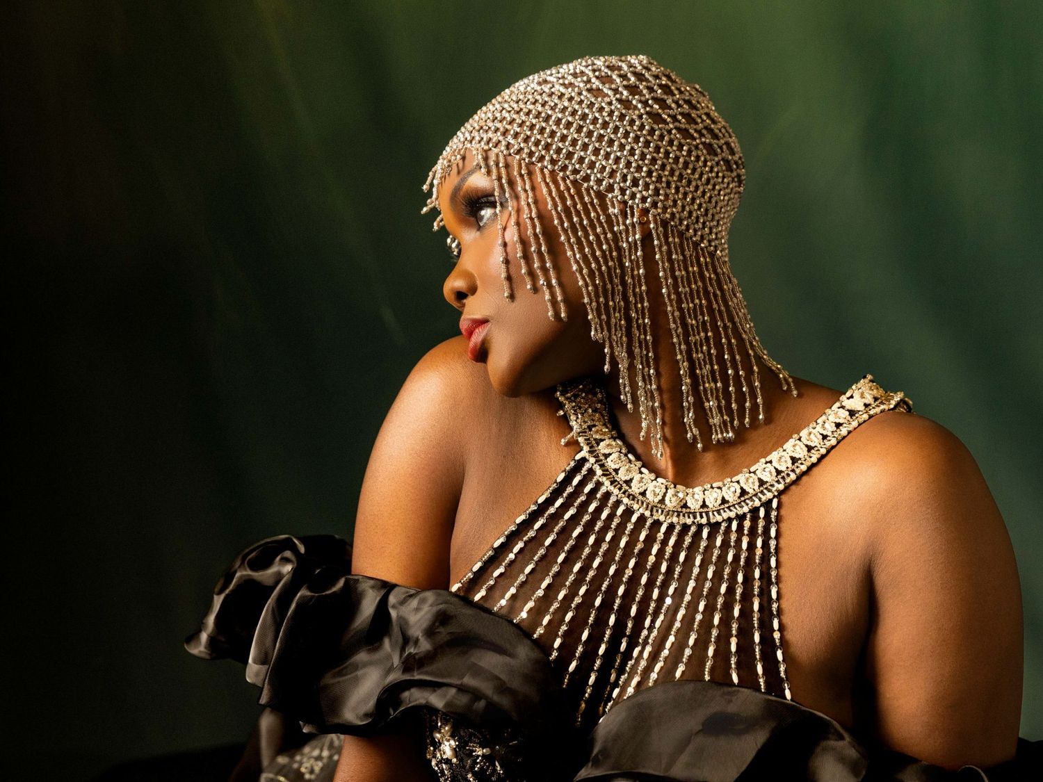 Woman with gold jewelry poses in multiple artistic portraits against dark background.
