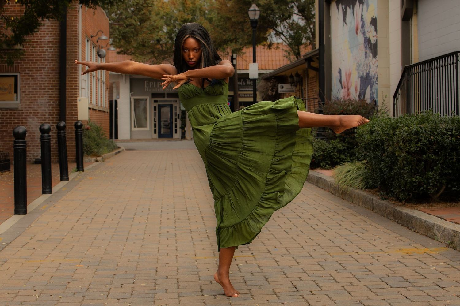 Dancer in flowing green dress performs outdoors on brick pathway in Marietta Square, Georgia
