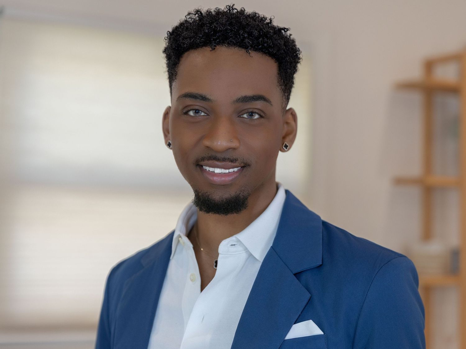 Professional headshot of someone wearing a navy blue blazer and white dress shirt with a warm smile.