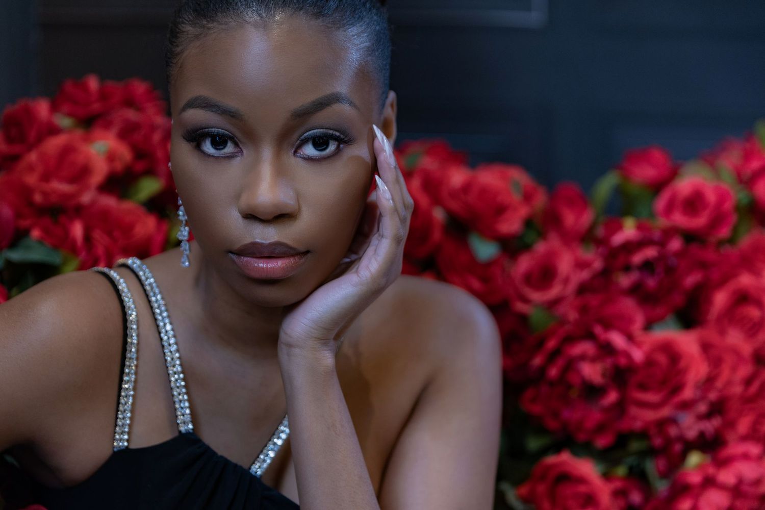 A collage of glamour portraits against a backdrop of vibrant red roses in dramatic lighting.