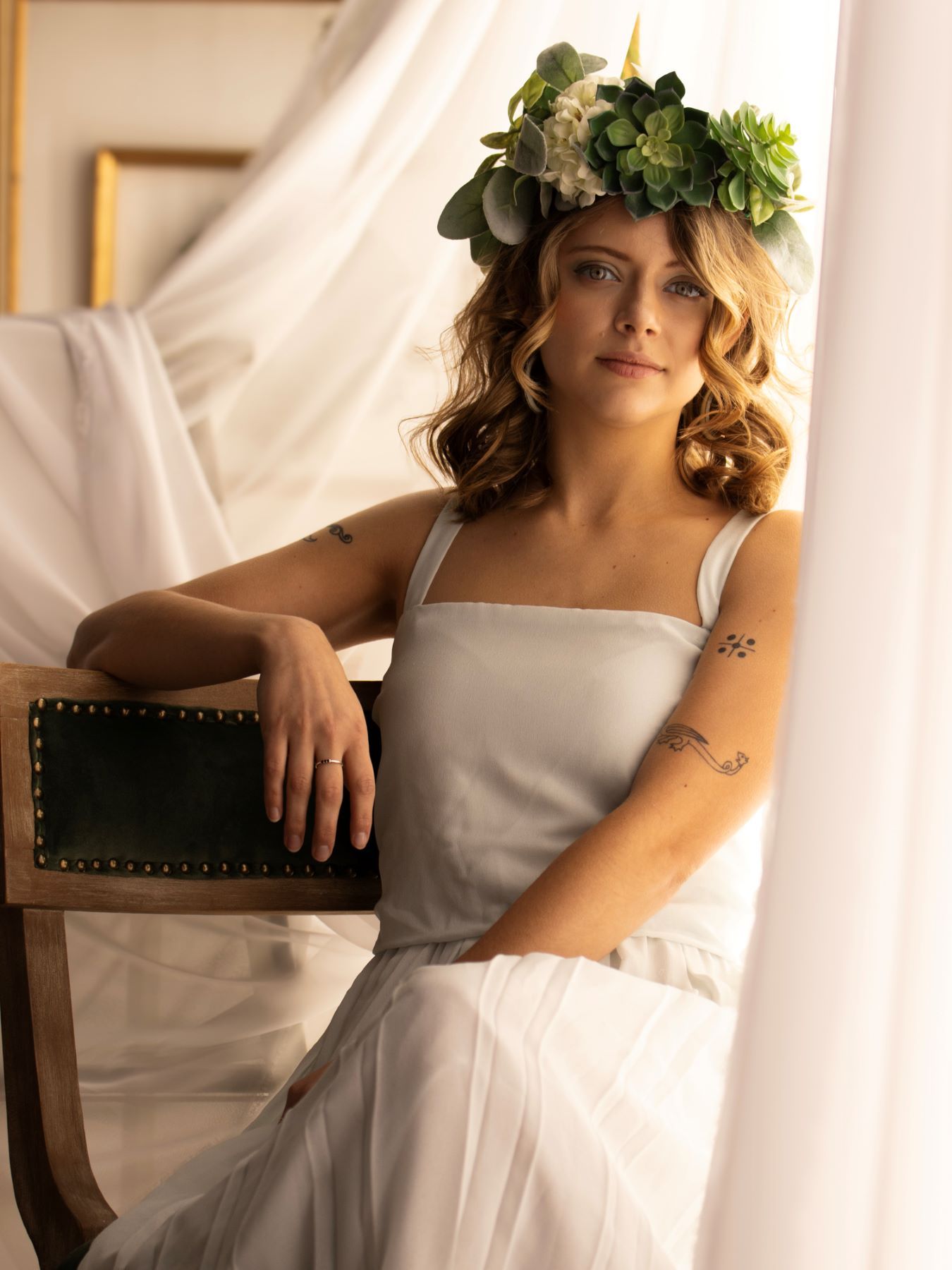 A series of romantic boudoir photos showing someone wearing a white dress and floral crown in soft lighting.