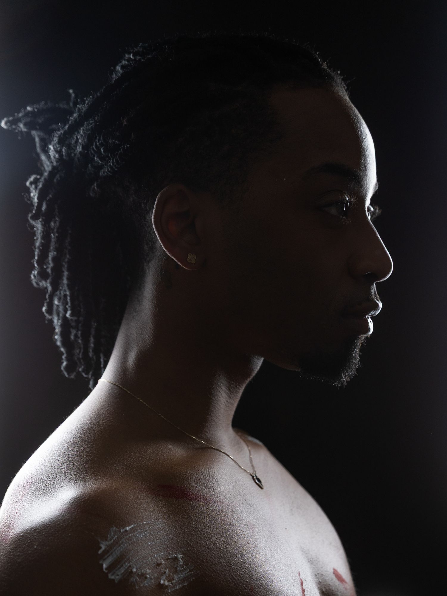 Dramatic side profile silhouette portraits against dark background with rim lighting highlighting facial features and hair.