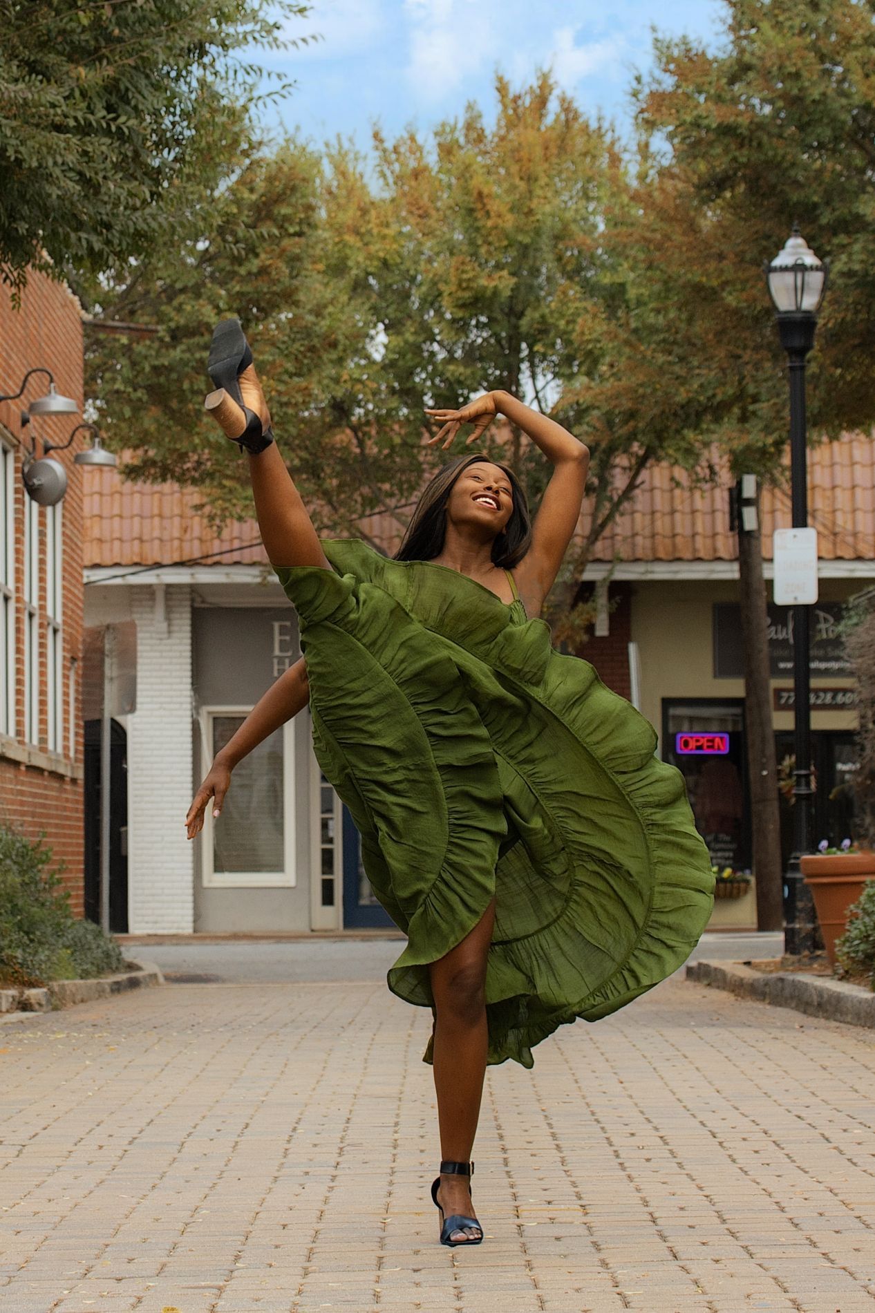 Dancer in olive dress strikes dynamic pose on outdoor Marietta Square, Georgia