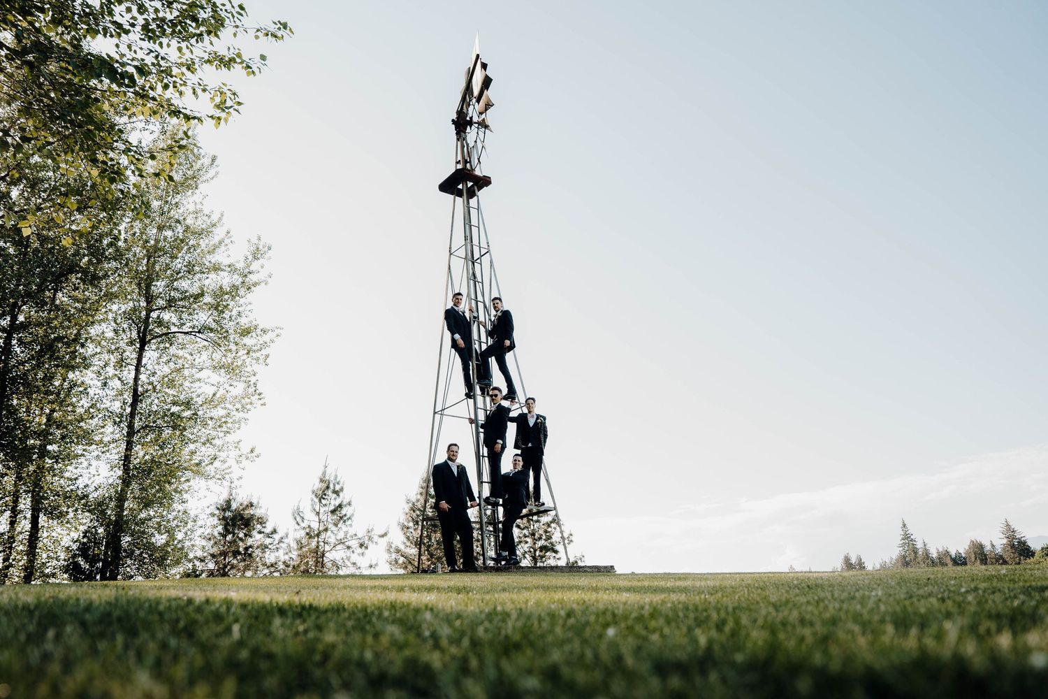 Cheerleaders perform a dramatic pyramid formation on a grassy field against a bright sky.