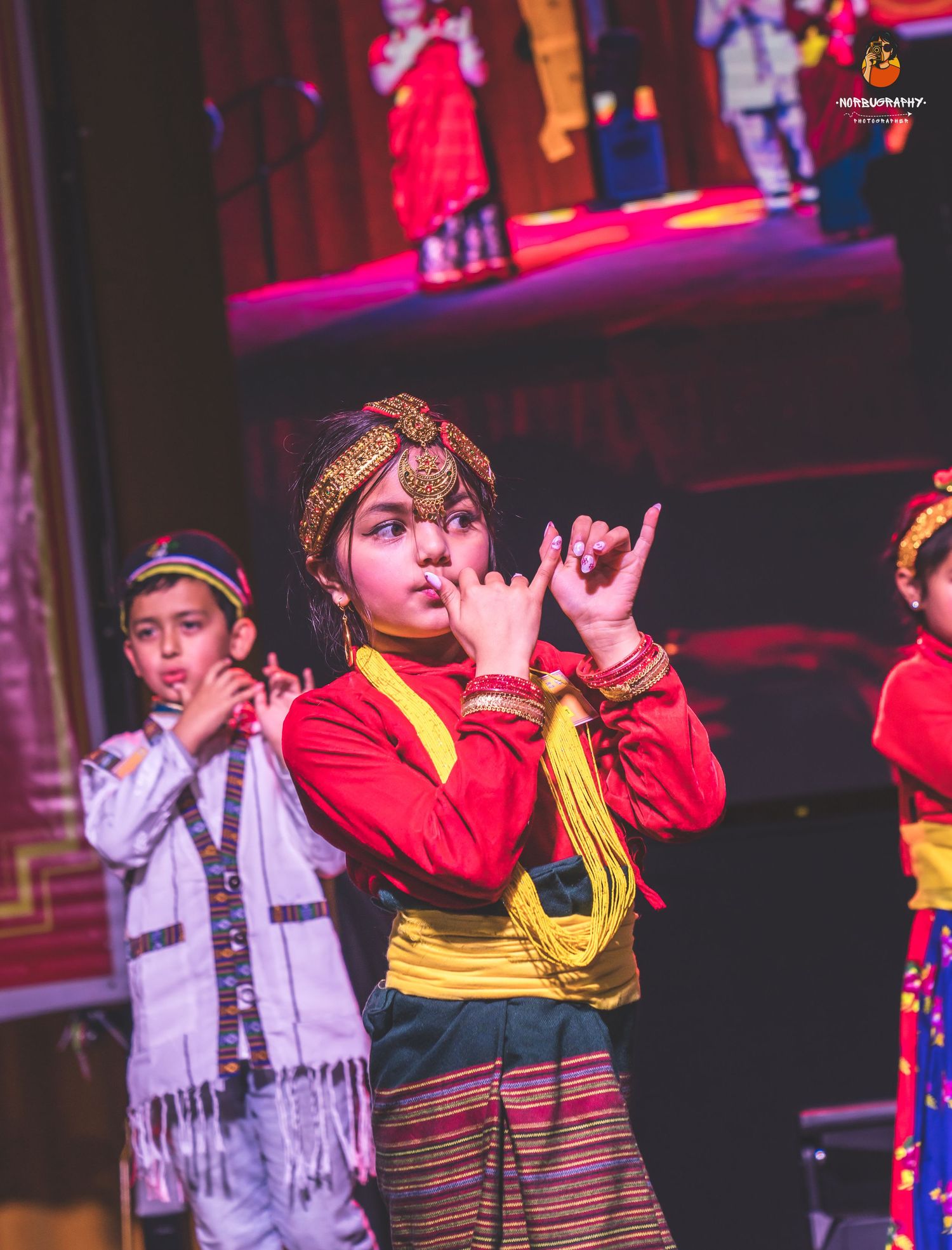 Traditional performers in colorful costumes during a cultural dance performance on stage.