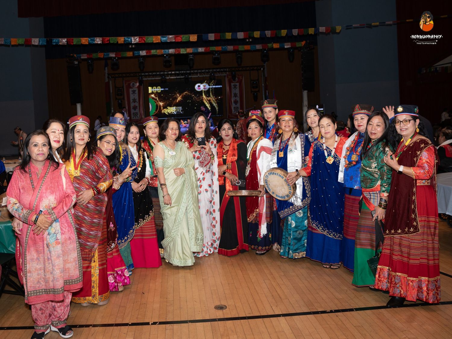 Large group photo of people wearing traditional colorful ethnic attire at a cultural celebration.