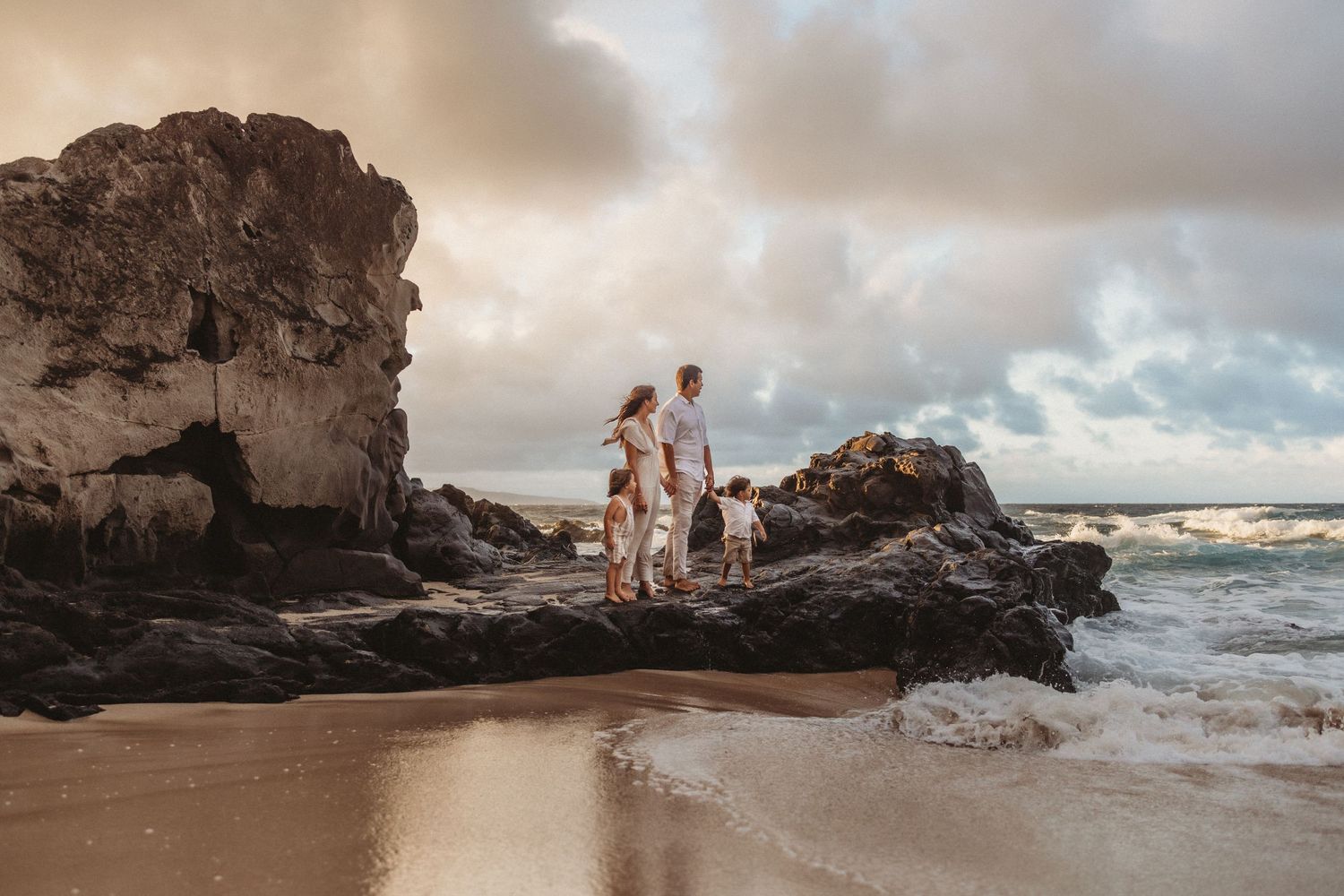 Maui lifestyle photographer captures family on rocks overlooking the ocean at sunset.