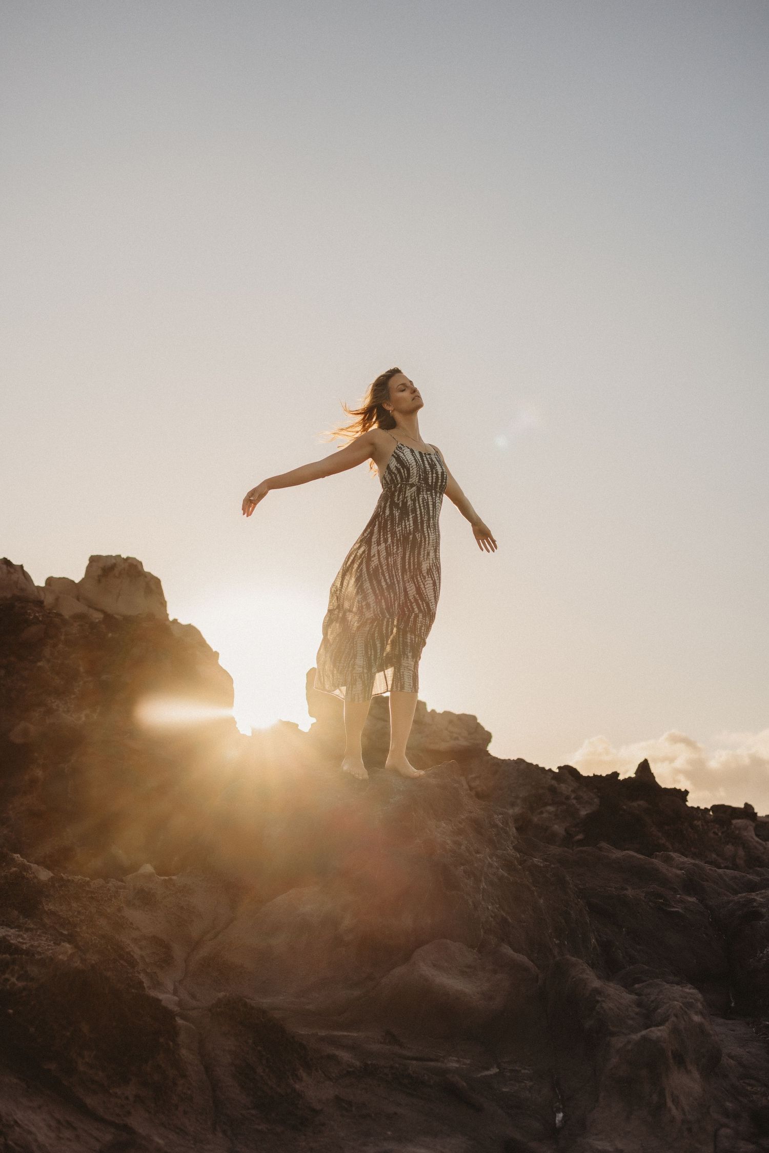 Editorial brand portrait of a woman standing on a coastal rock.
