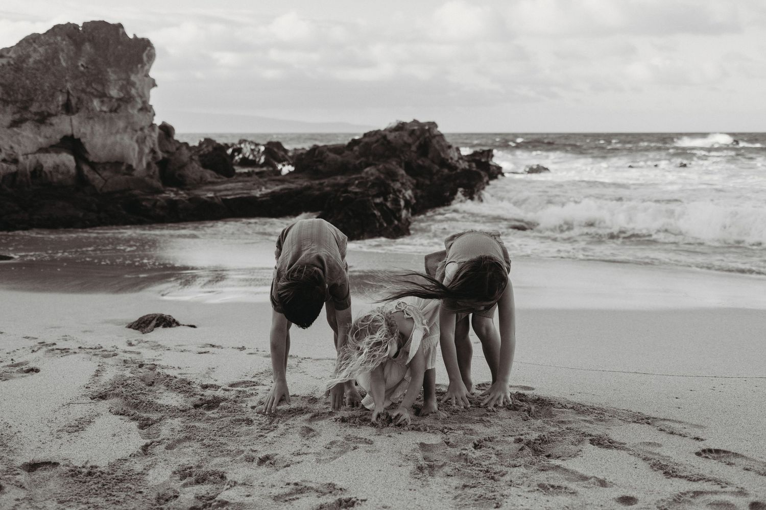 Maui family photography of children playing in the sand by the beach.