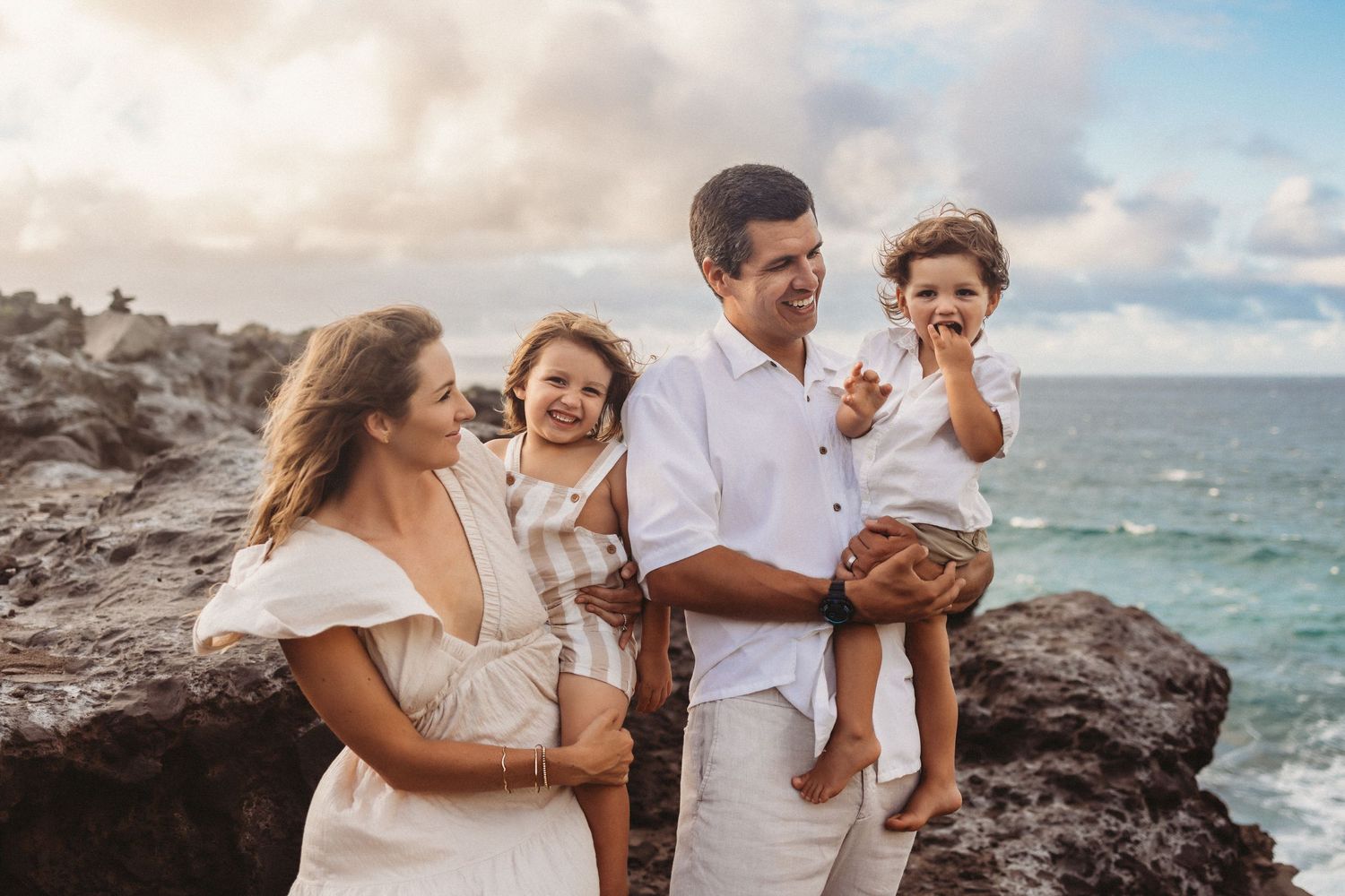 Maui family photography of parents holding children by the beach and rocks.