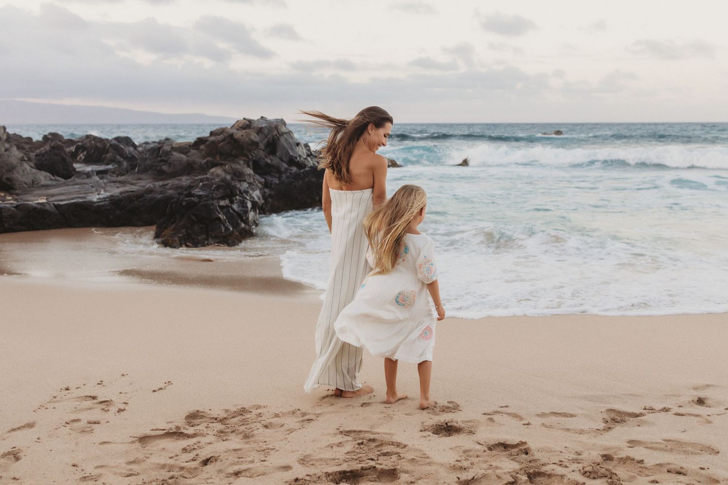 Maui lifestyle photographer captures mother and daughter by shoreline facing ocean view.