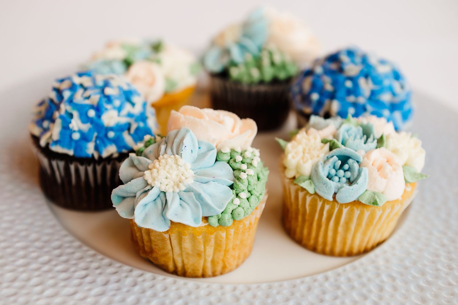 ecorative cupcakes topped with colorful floral designs.