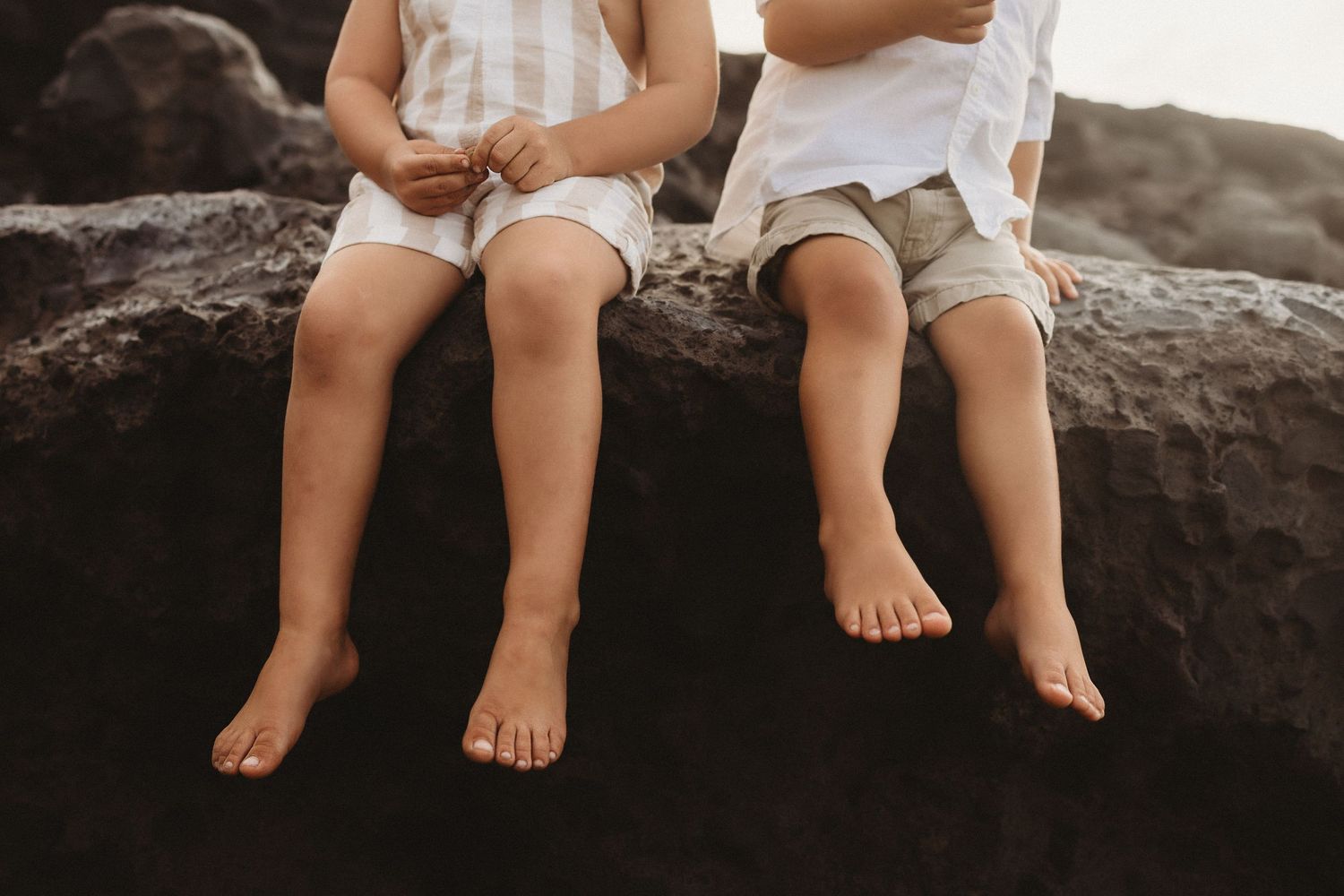 Candid Maui portrait detail of kids sitting on a rock with legs dangling.