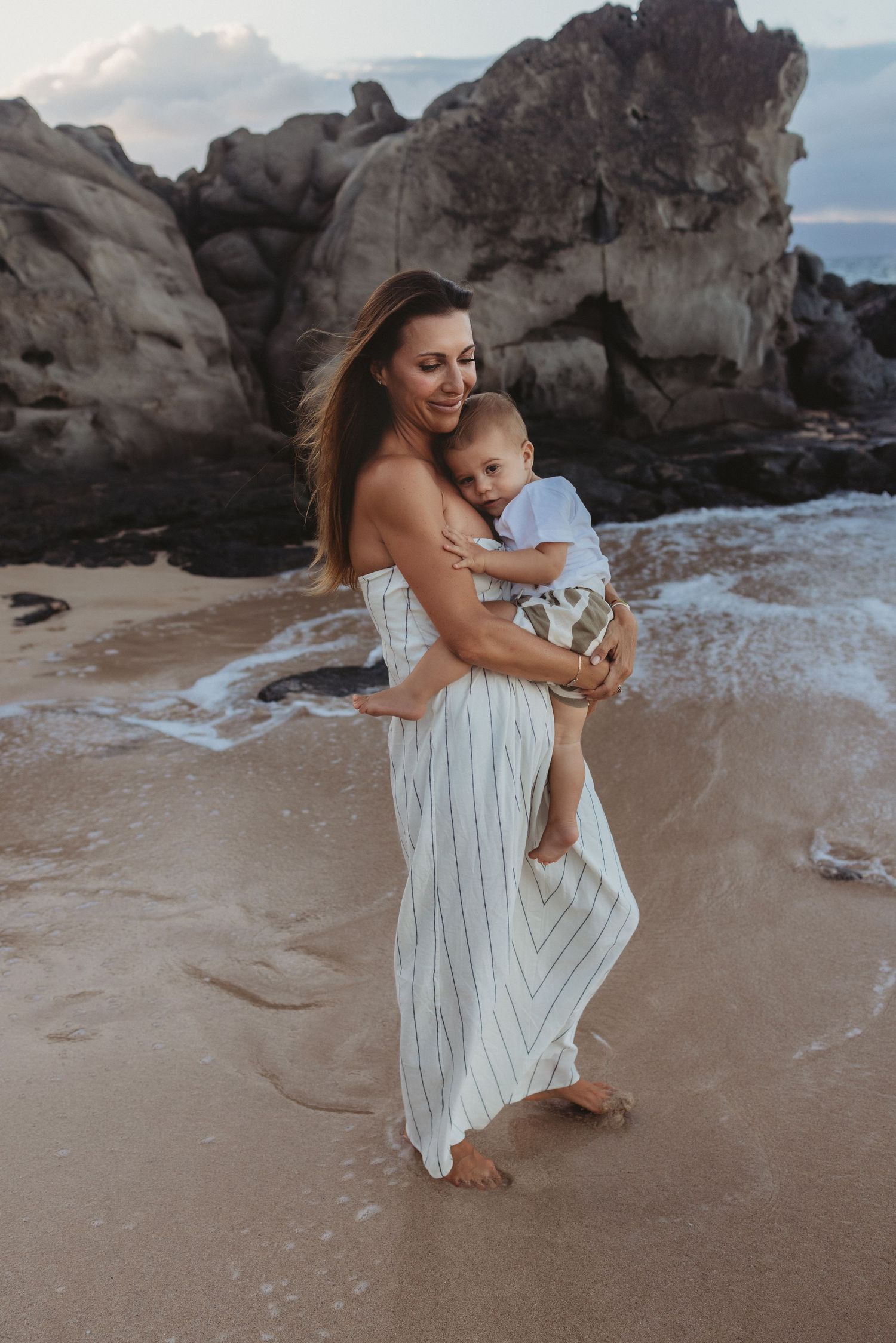 Heartfelt Maui family photo of mother and son swaying together on the beach.