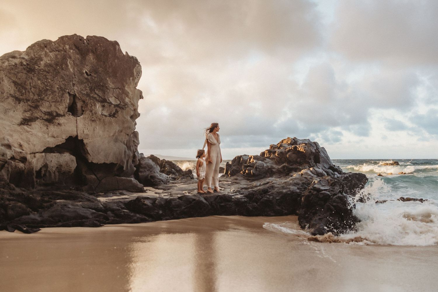 Maui lifestyle photographer captures mom and son on rocks overlooking the ocean at sunset.