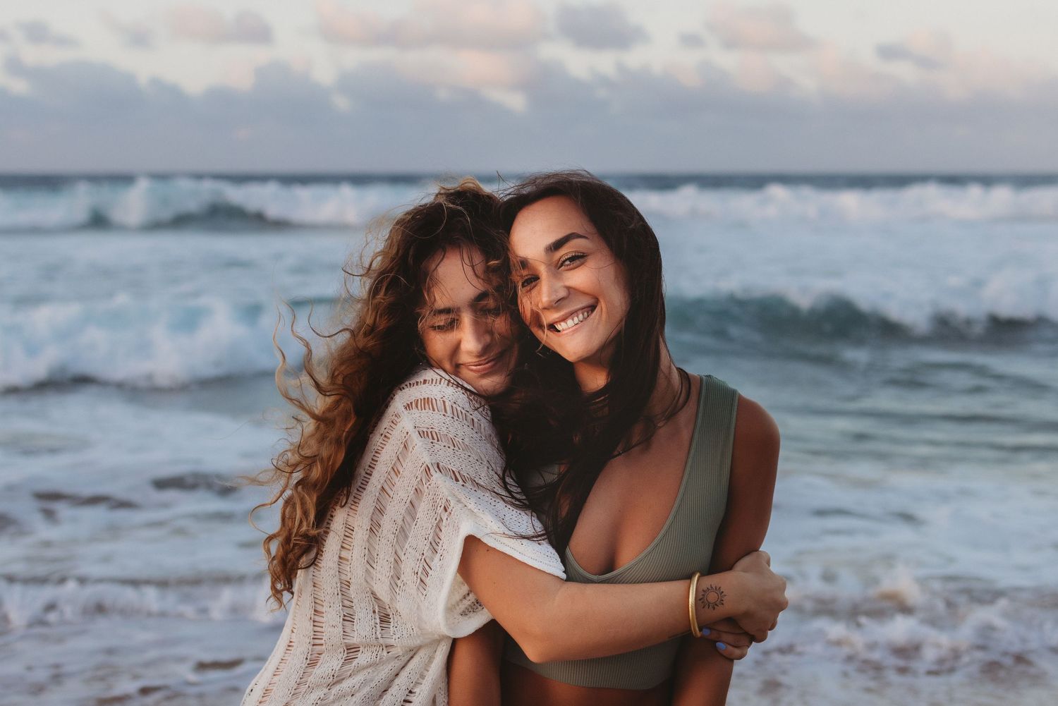 Candid Maui portrait of two sisters sharing a fun hug on the beach.