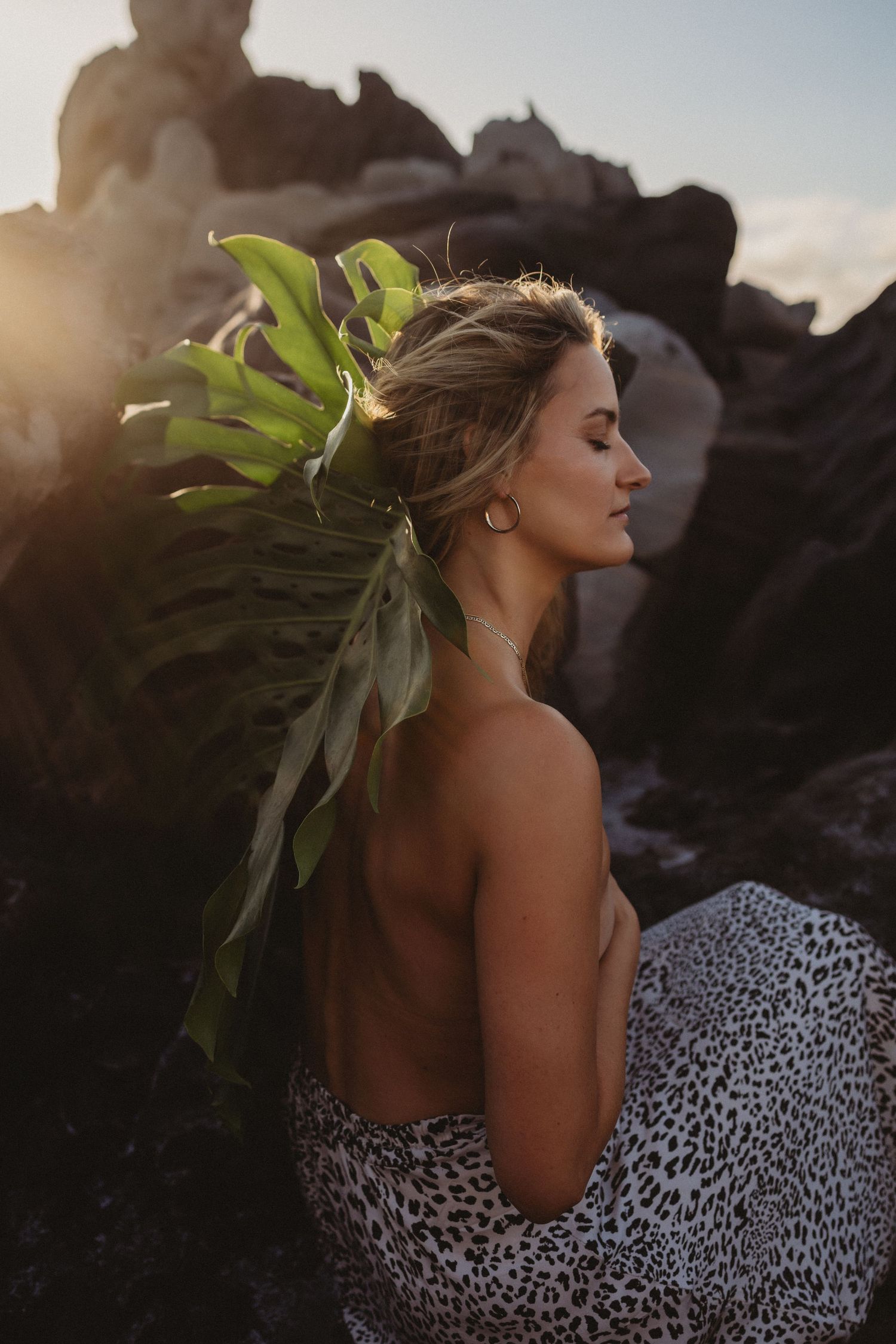 ditorial Maui brand photo of woman with leaf, eyes closed in golden hour light.