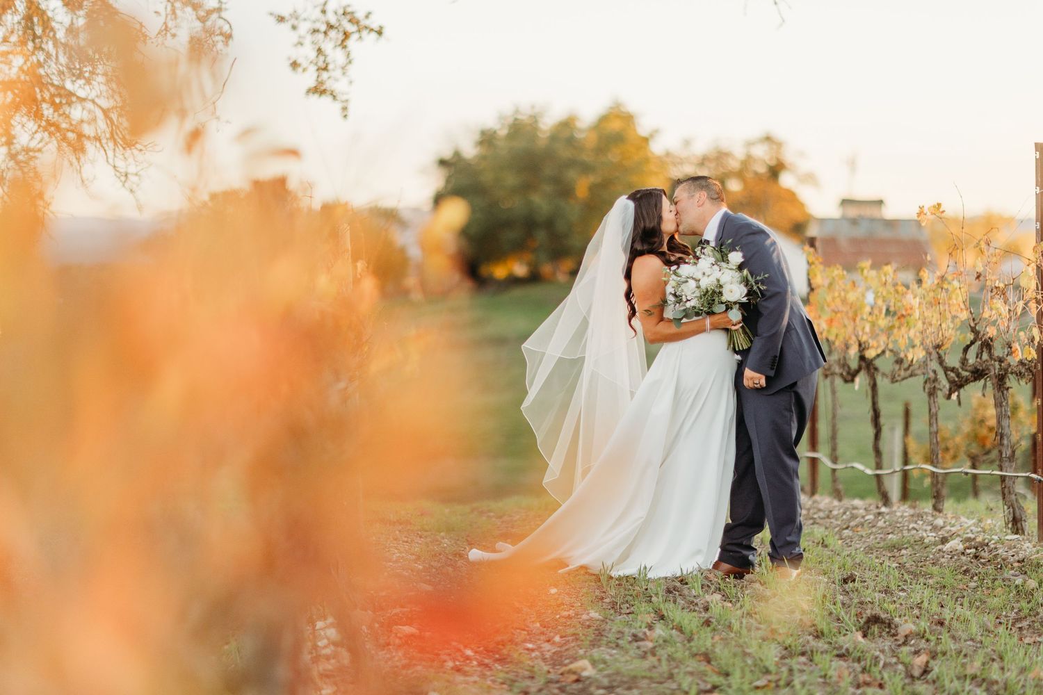 Golden sunset light illuminates couple during outdoor autumn wedding portraits.