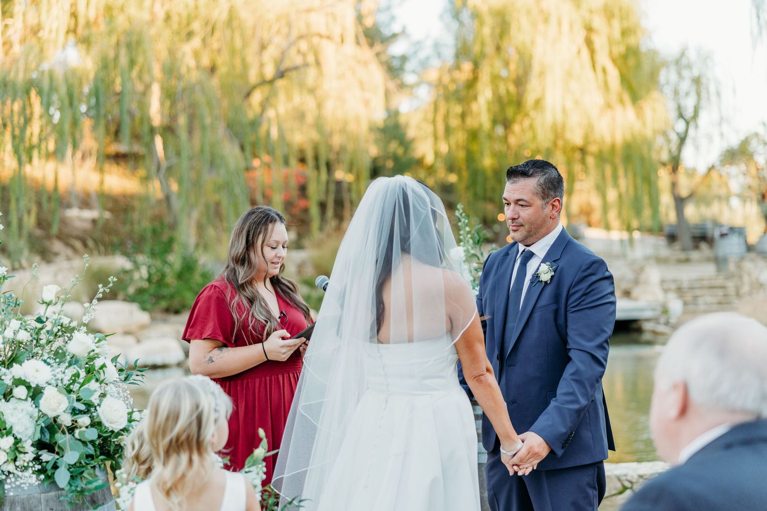 Wedding couple shares romantic moments in a golden sunset garden setting with white floral decor and elegant attire.