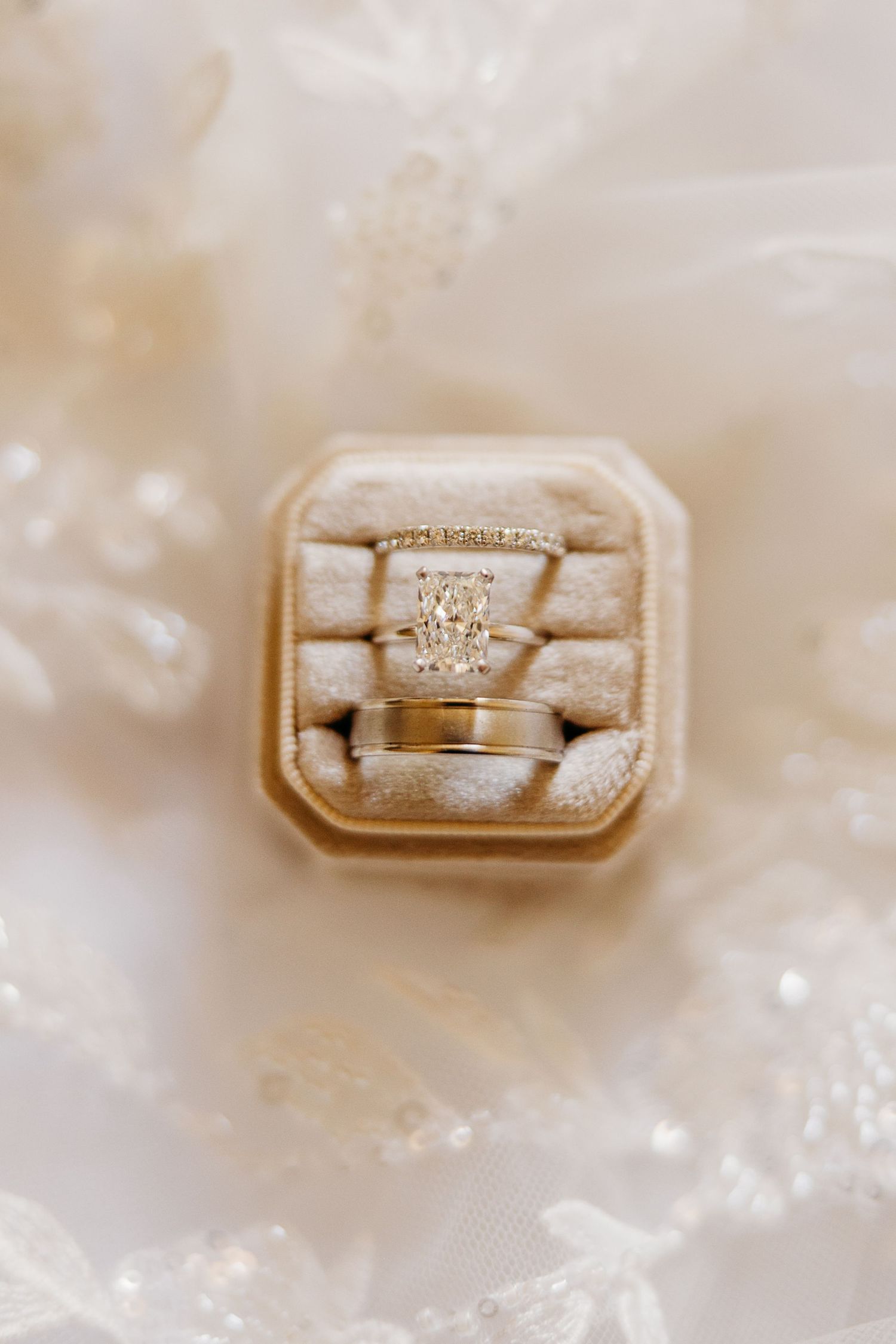 Close-up view of a diamond engagement ring in a beige velvet ring box.