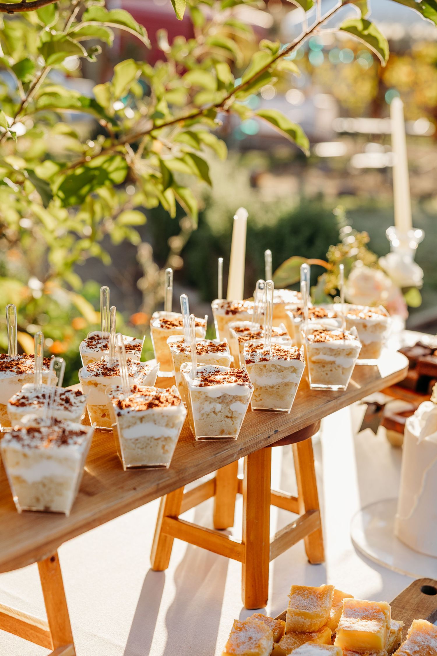 Row of beautifully presented white appetizer boxes arranged on wooden display at outdoor event.
