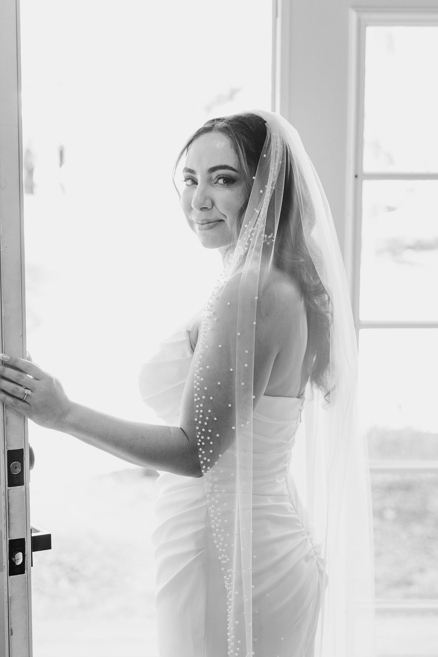 An elegant bridal portrait showing a sparkly veil near a bright window.