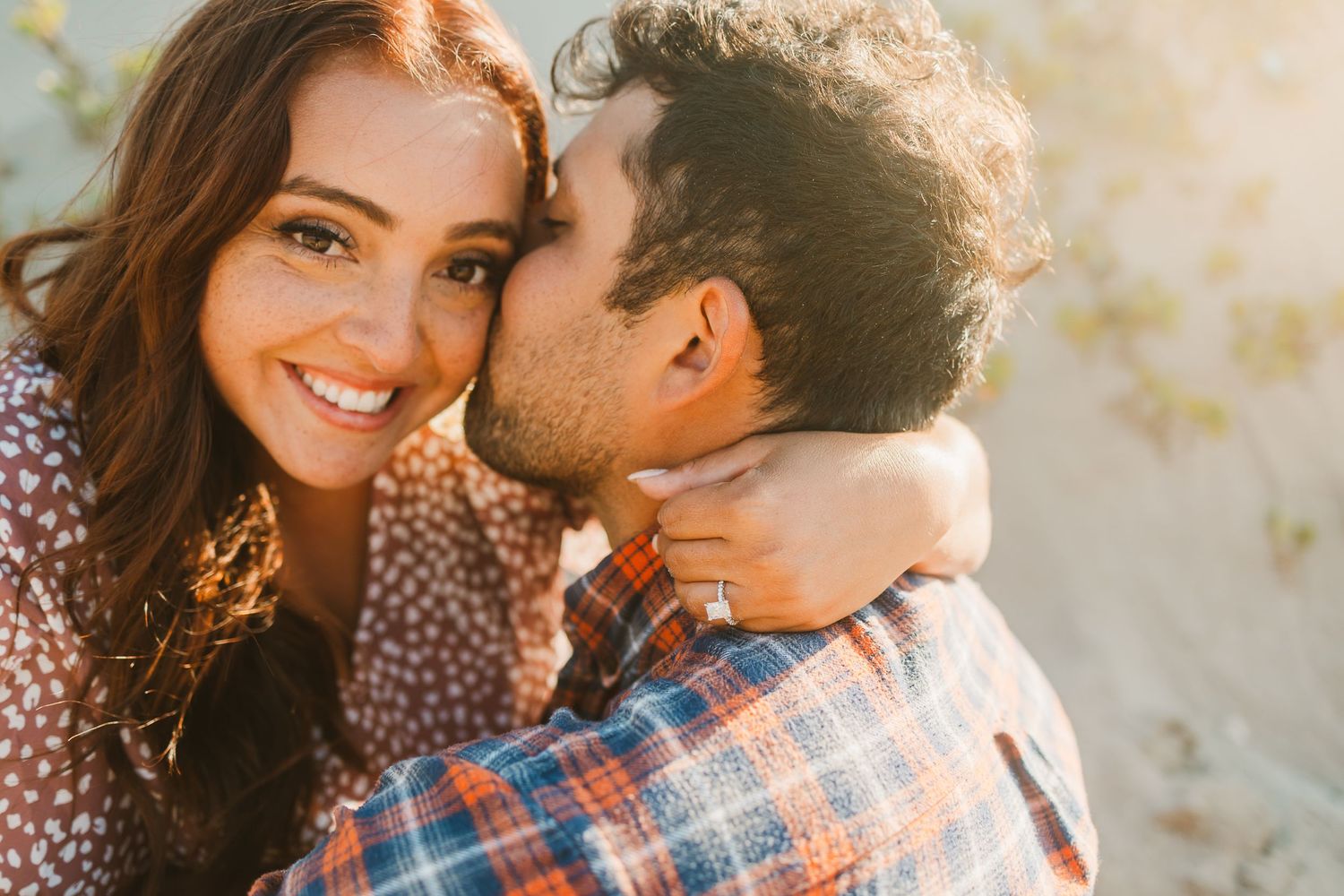 Couple sharing a tender moment in golden sunlight against a desert backdrop.