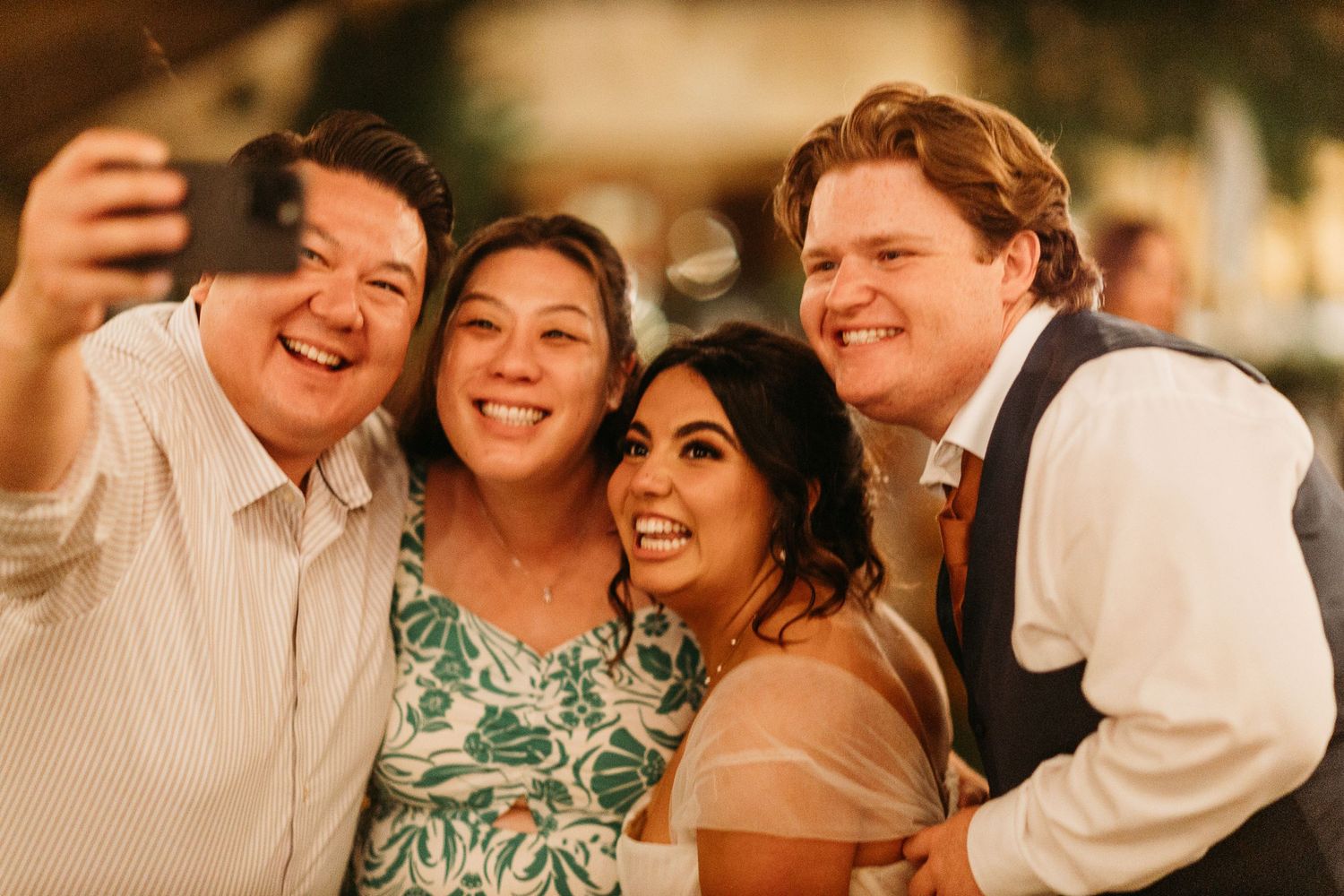 Wedding guests taking a cheerful selfie together during reception celebrations.