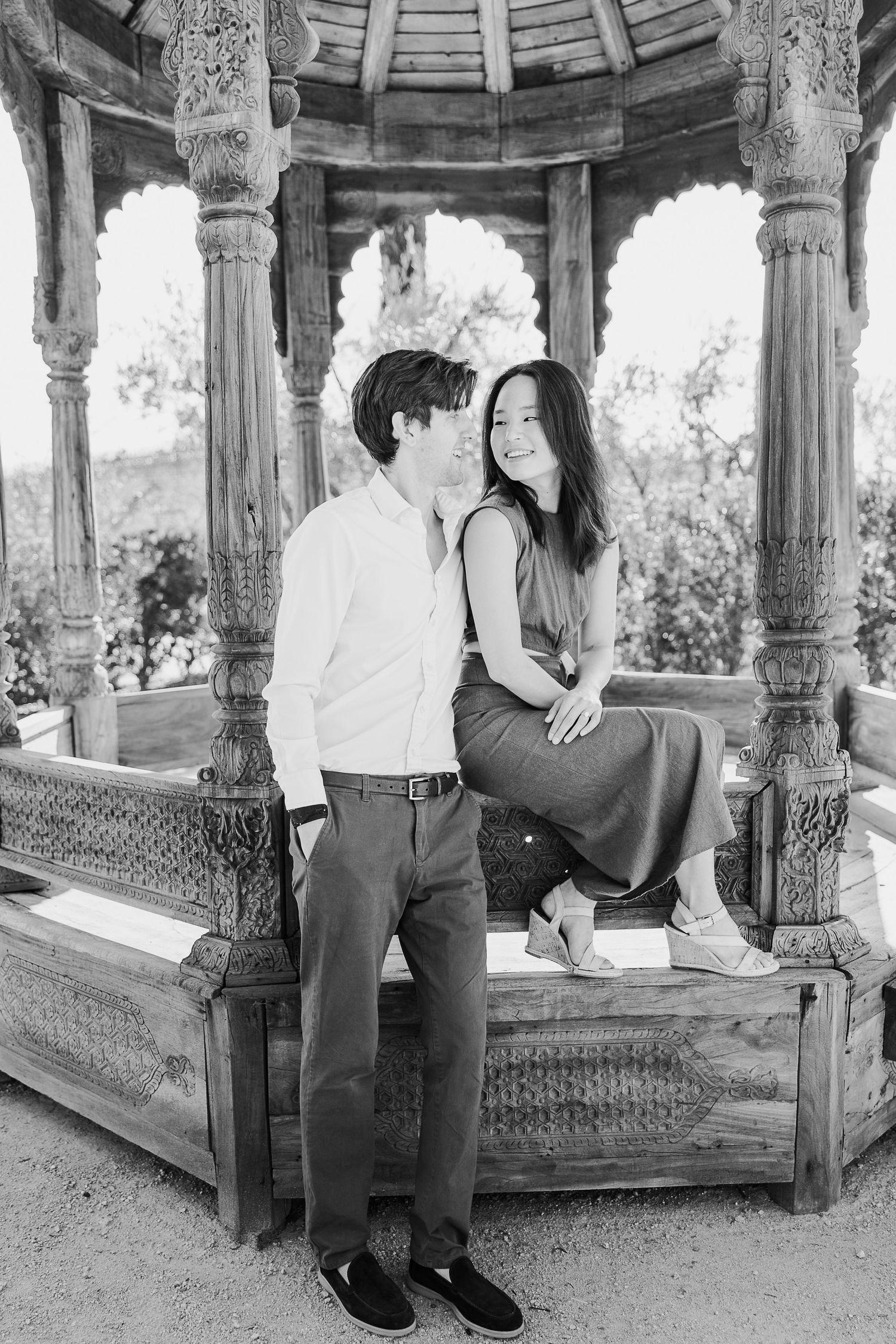 Couple sharing an intimate moment in a decorative gazebo with ornate pillars.