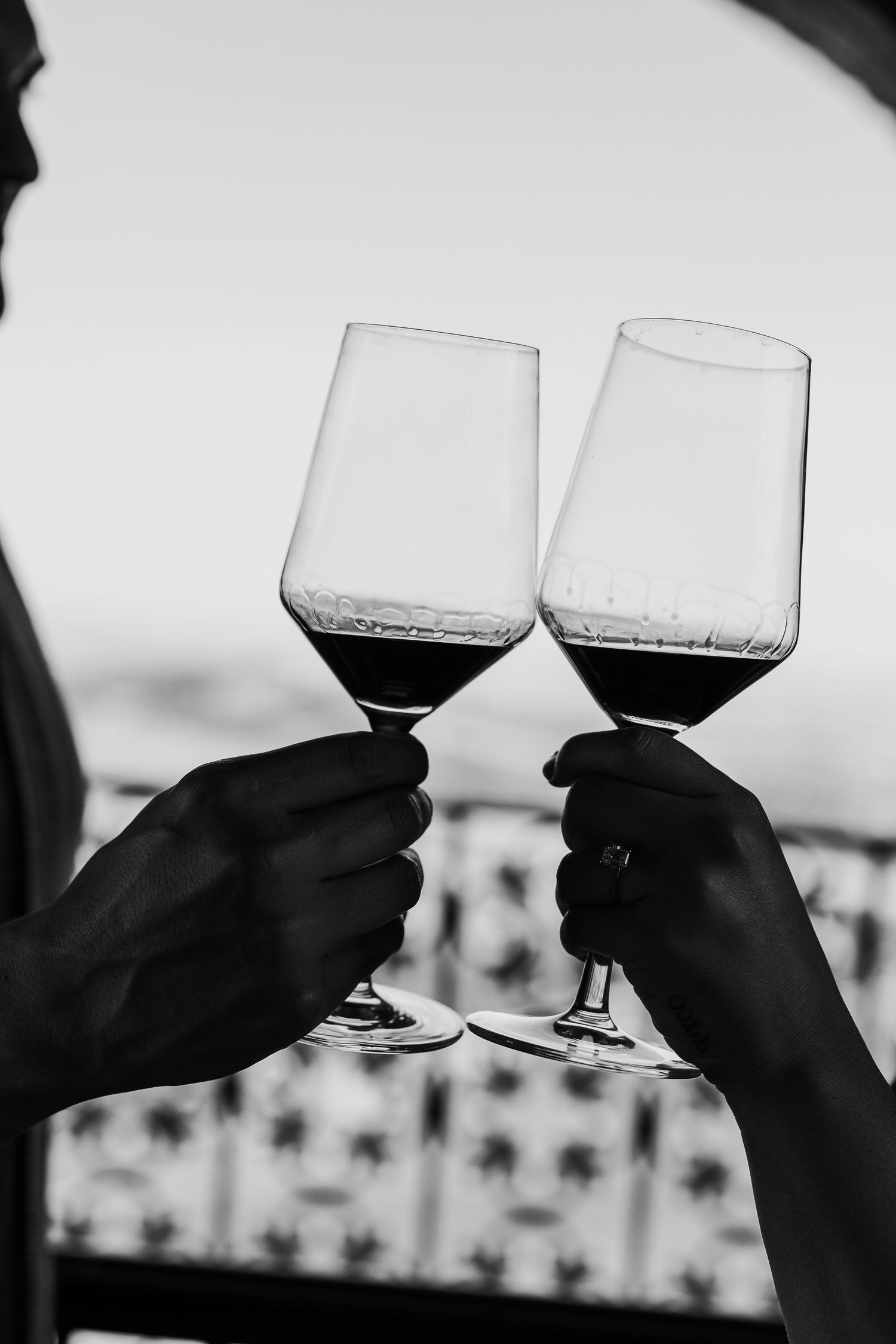 Silhouettes of hands toasting wine glasses against a bright background.