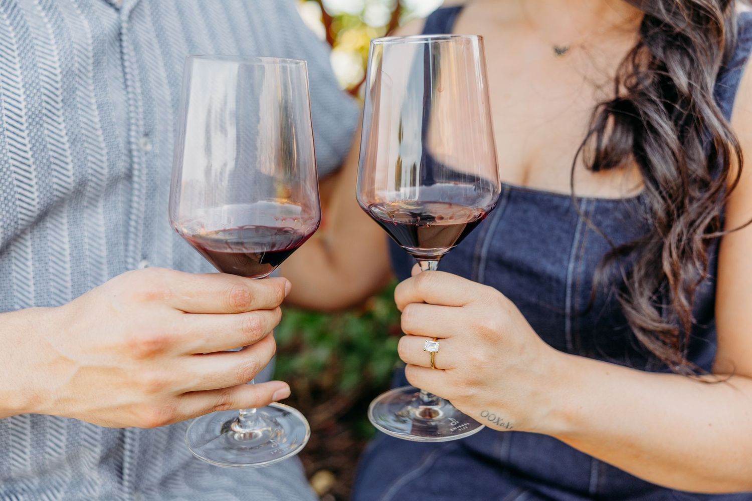 Two hands clink wine glasses together during an intimate outdoor wine tasting experience.