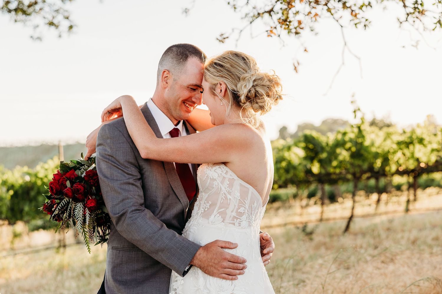 A tender moment between newlyweds in a sun-drenched vineyard.