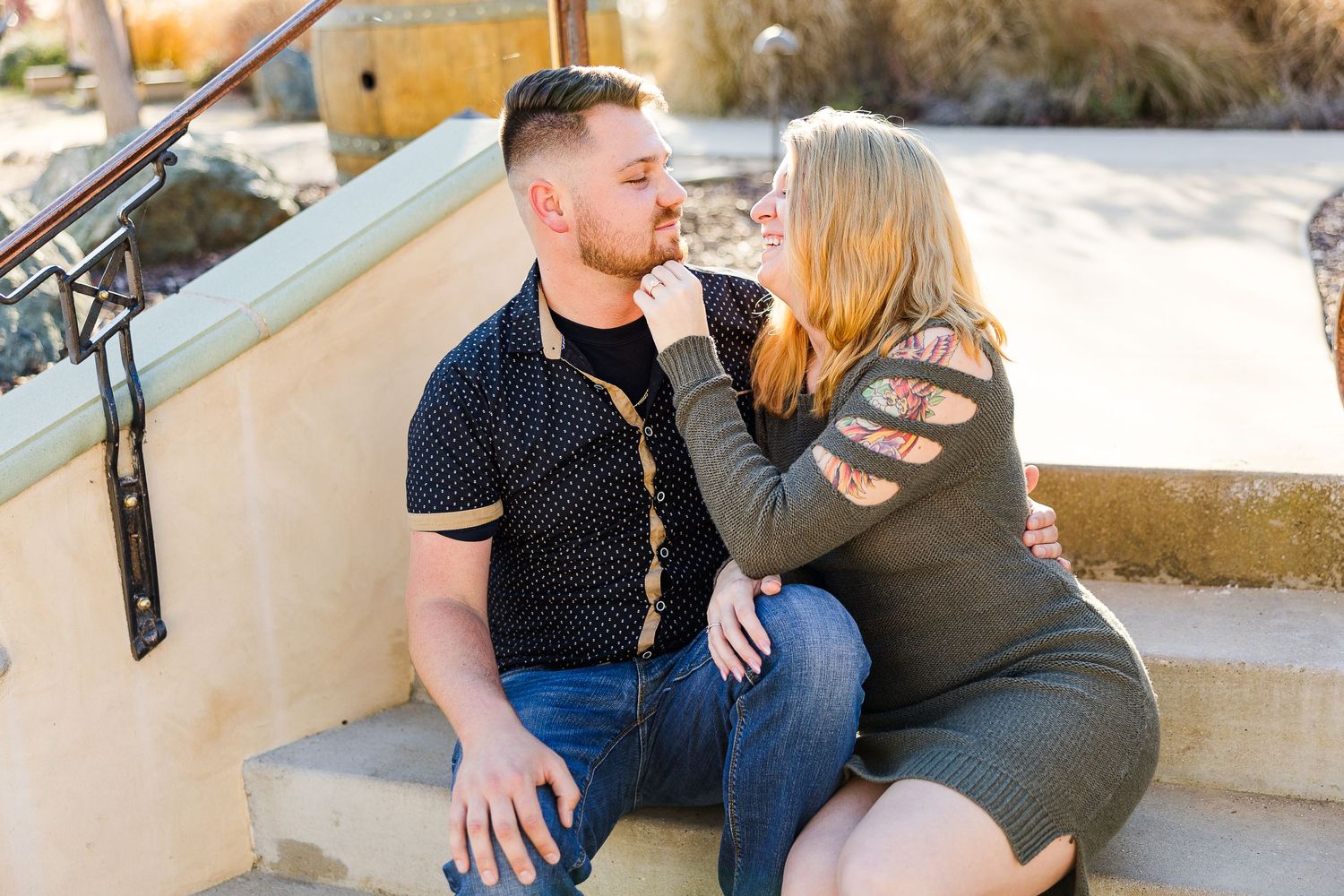 A romantic couple embraces while seated on outdoor steps during a photo session.