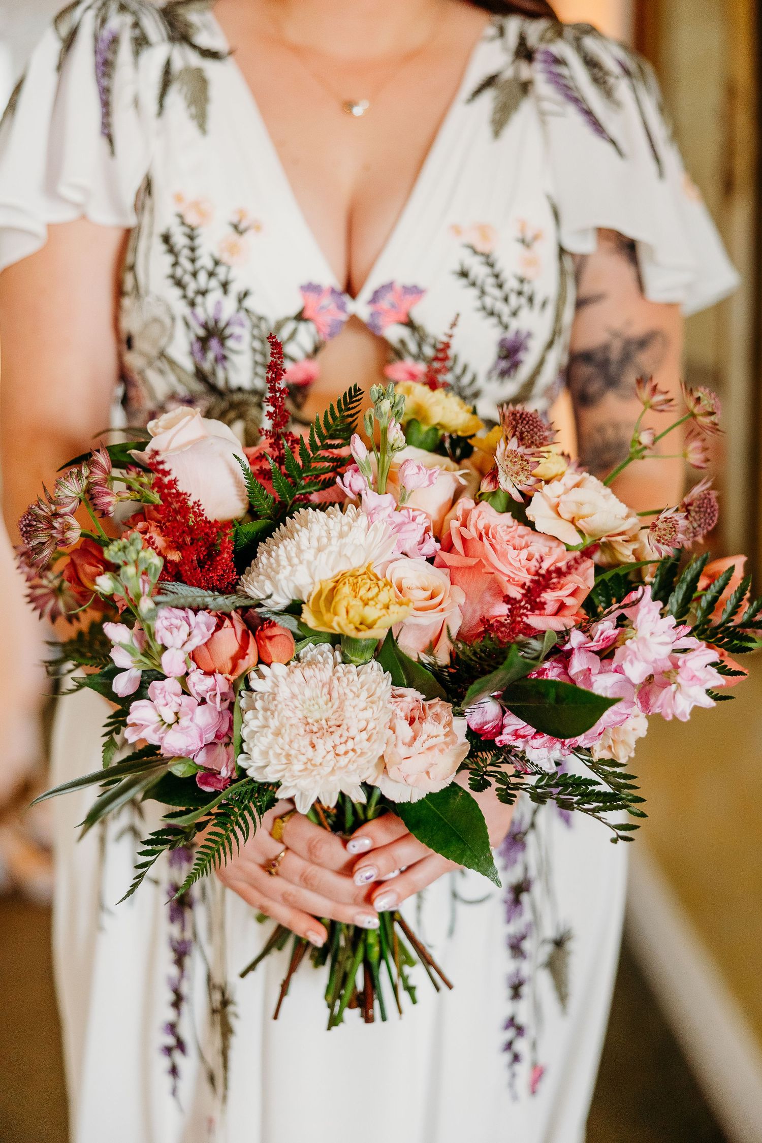 A row of beautiful wedding bouquets featuring pink, peach and red flowers with greenery.