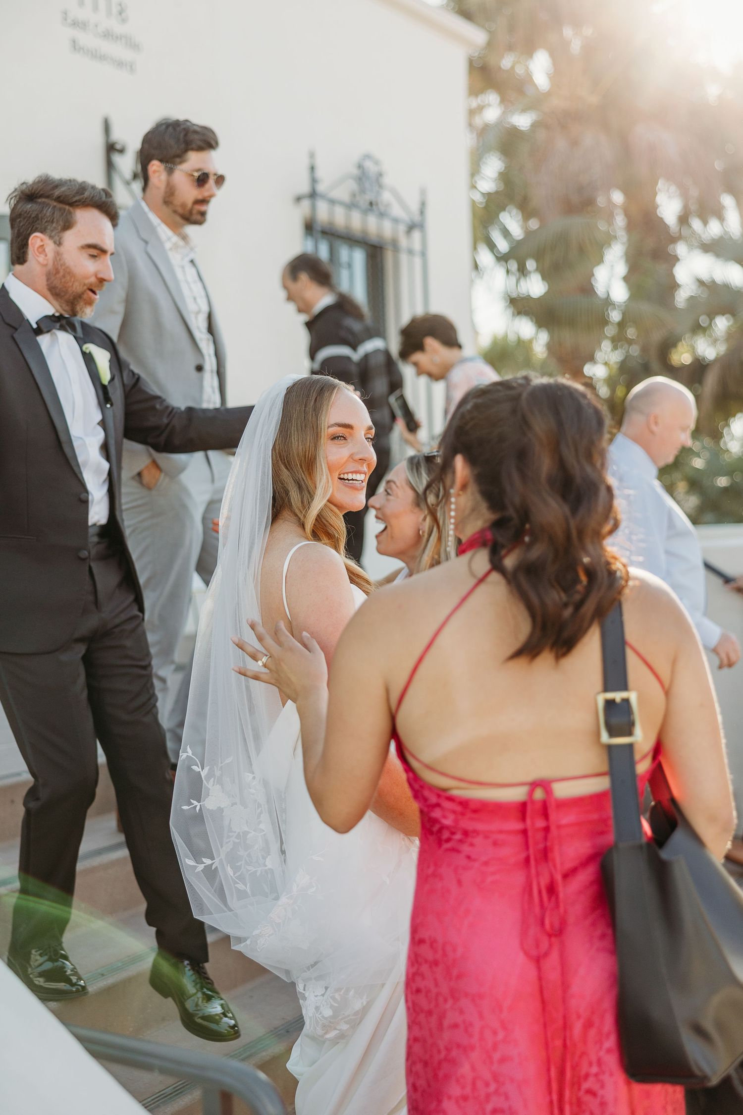 Wedding guests mingling and celebrating during an outdoor reception in golden sunlight.
