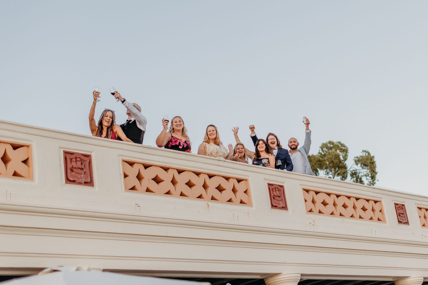 A group of people cheer and wave from a balcony during a celebration event.