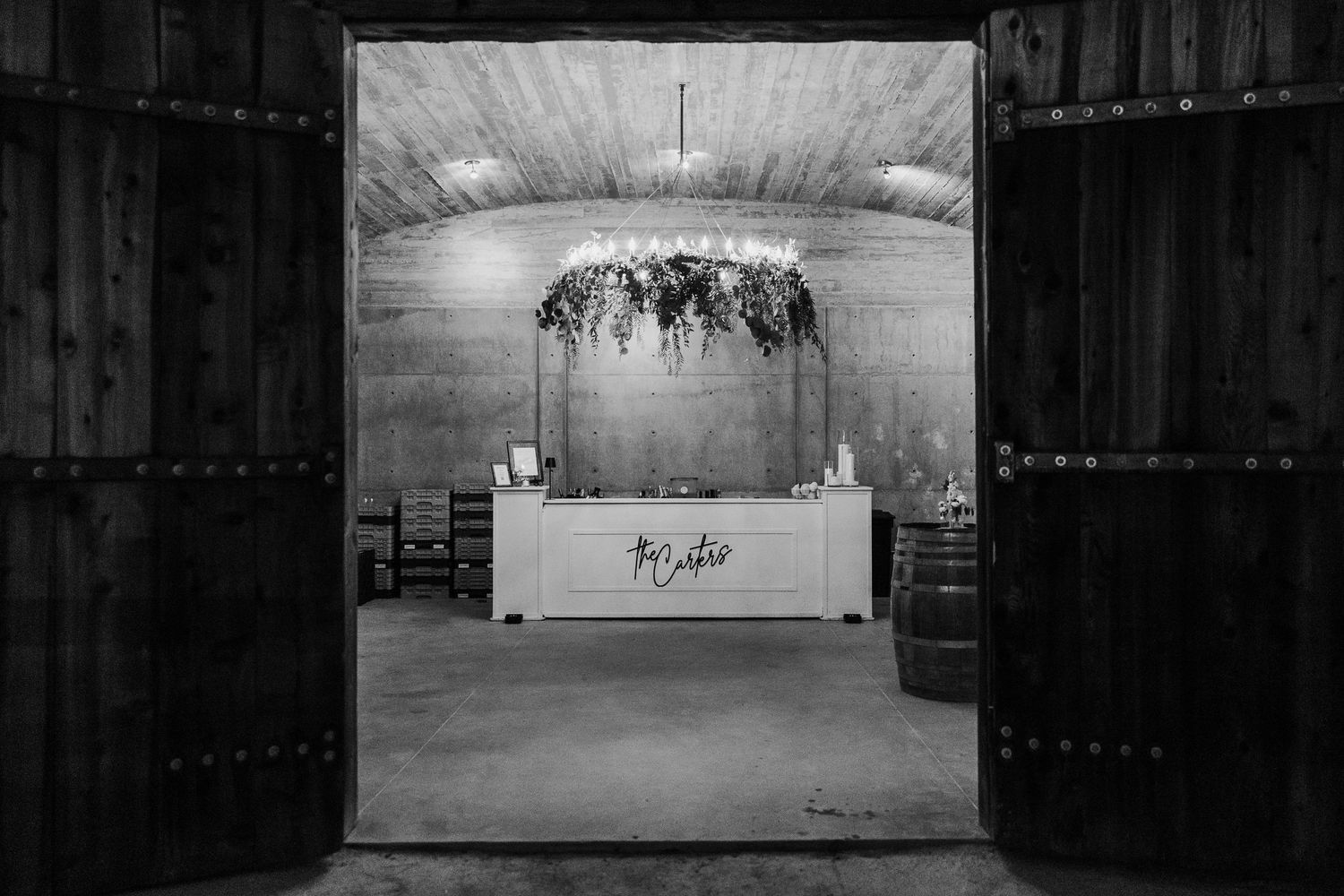 A rustic barn interior with hanging floral decorations and vintage architectural details.