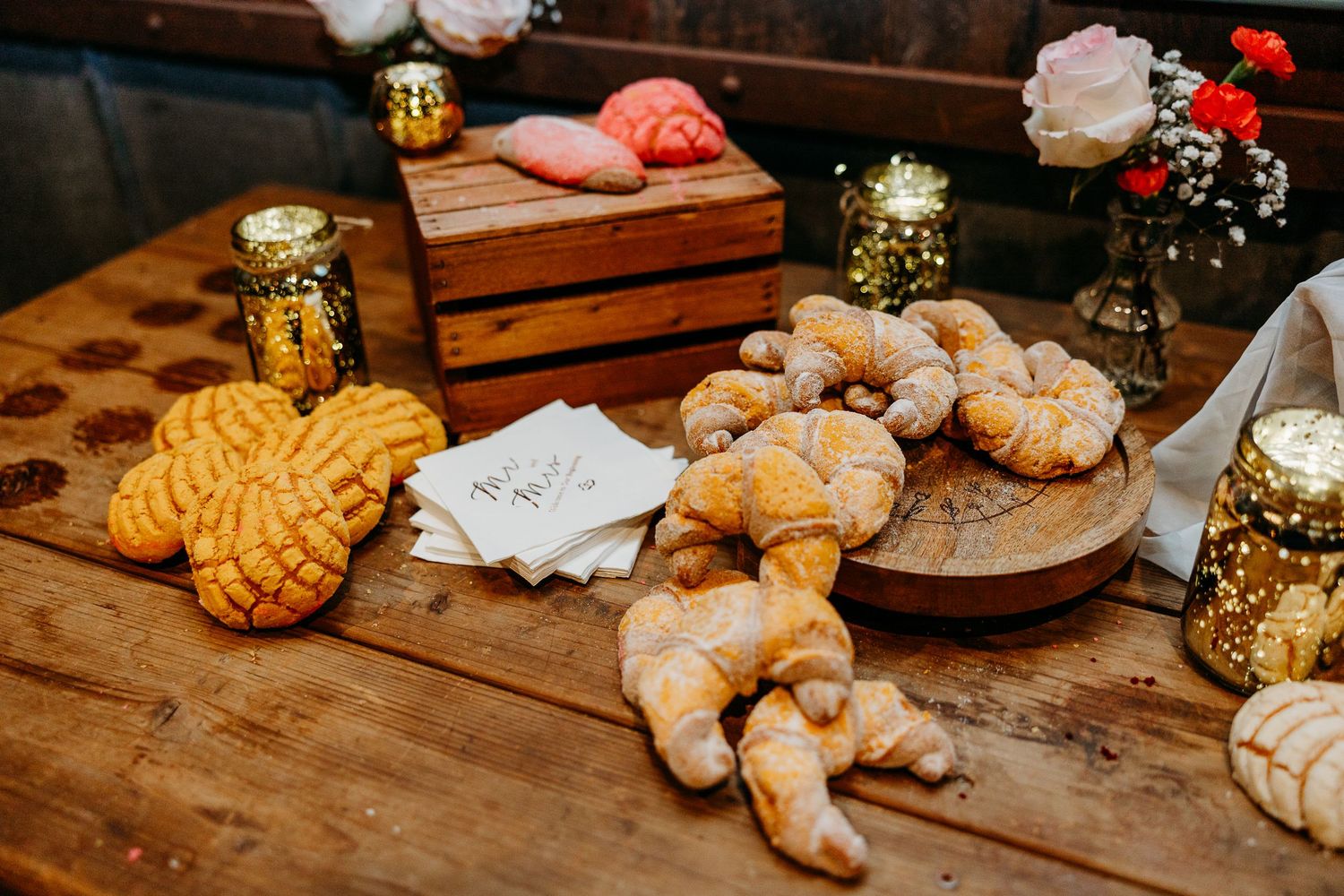 Homemade cookies and desserts displayed on wooden tables at a rustic wedding reception.
